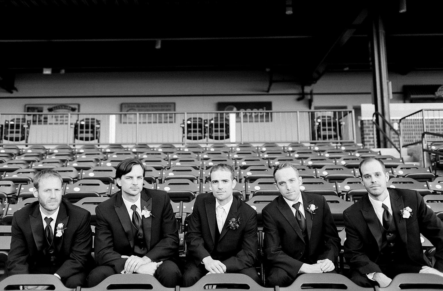Arielle Peters Photography | Groom and groomsmen sitting on bleachers at Parkview Field on wedding day in Fort Wayne, Indiana.