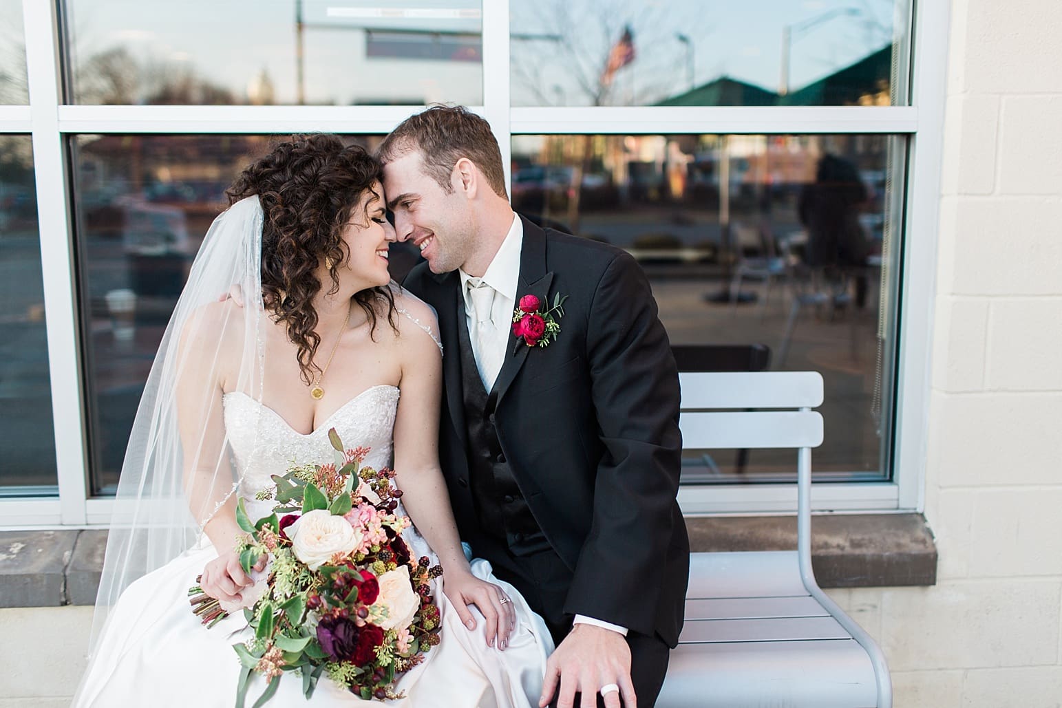 Arielle Peters Photography | Bride and groom sitting outside on bench on wedding day at Baker Street Train Station in Fort Wayne, Indiana.