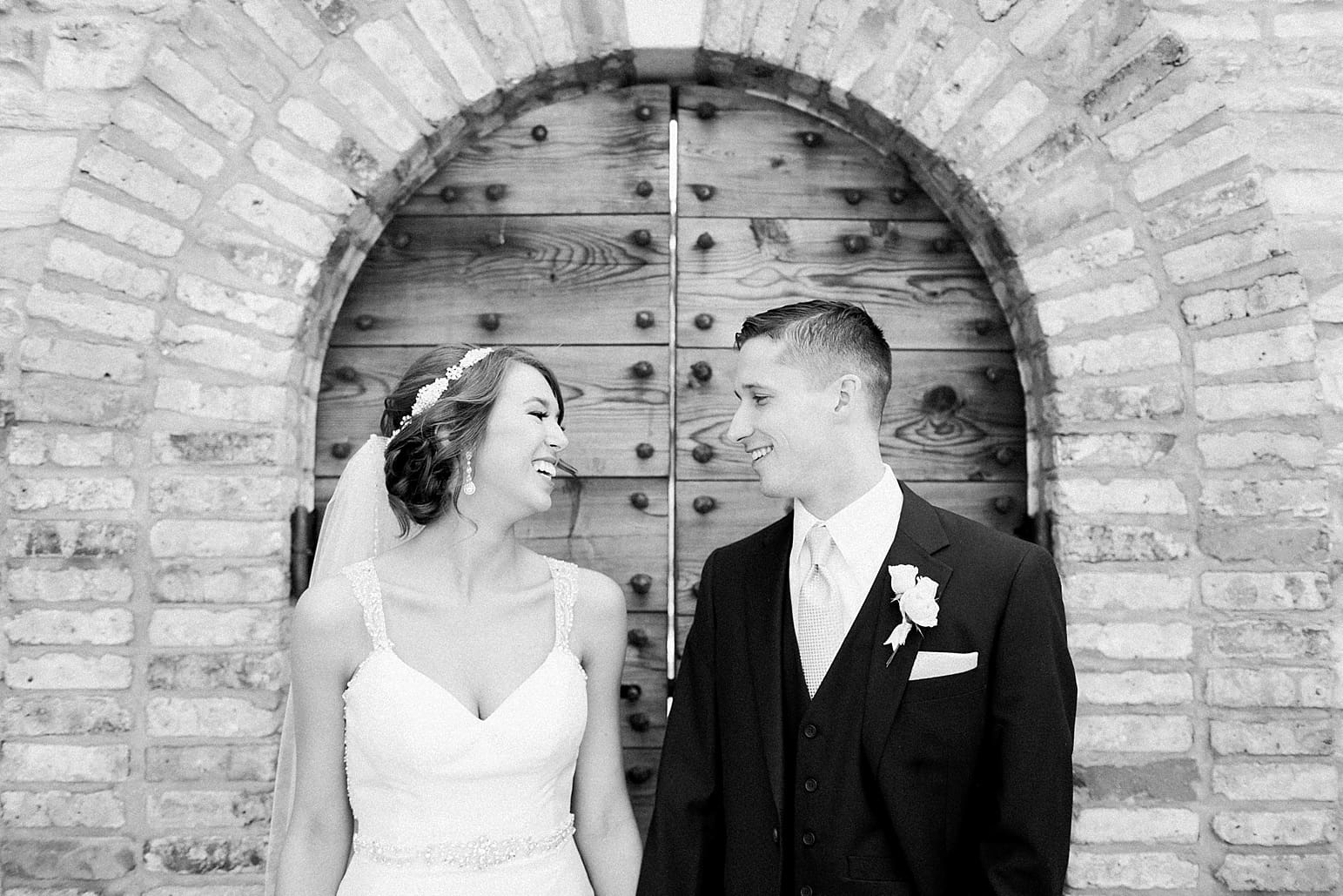 Arielle Peters Photography | Bride and groom laughing in front of old wooden door on wedding day at The Market in Valparaiso, Indiana.