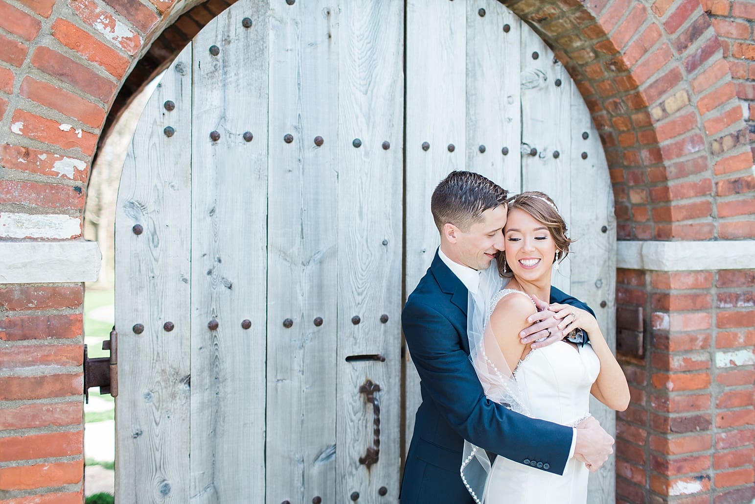 Arielle Peters Photography | Groom holding bride laughing in front of old wooden door on wedding day at The Market in Valparaiso, Indiana.
