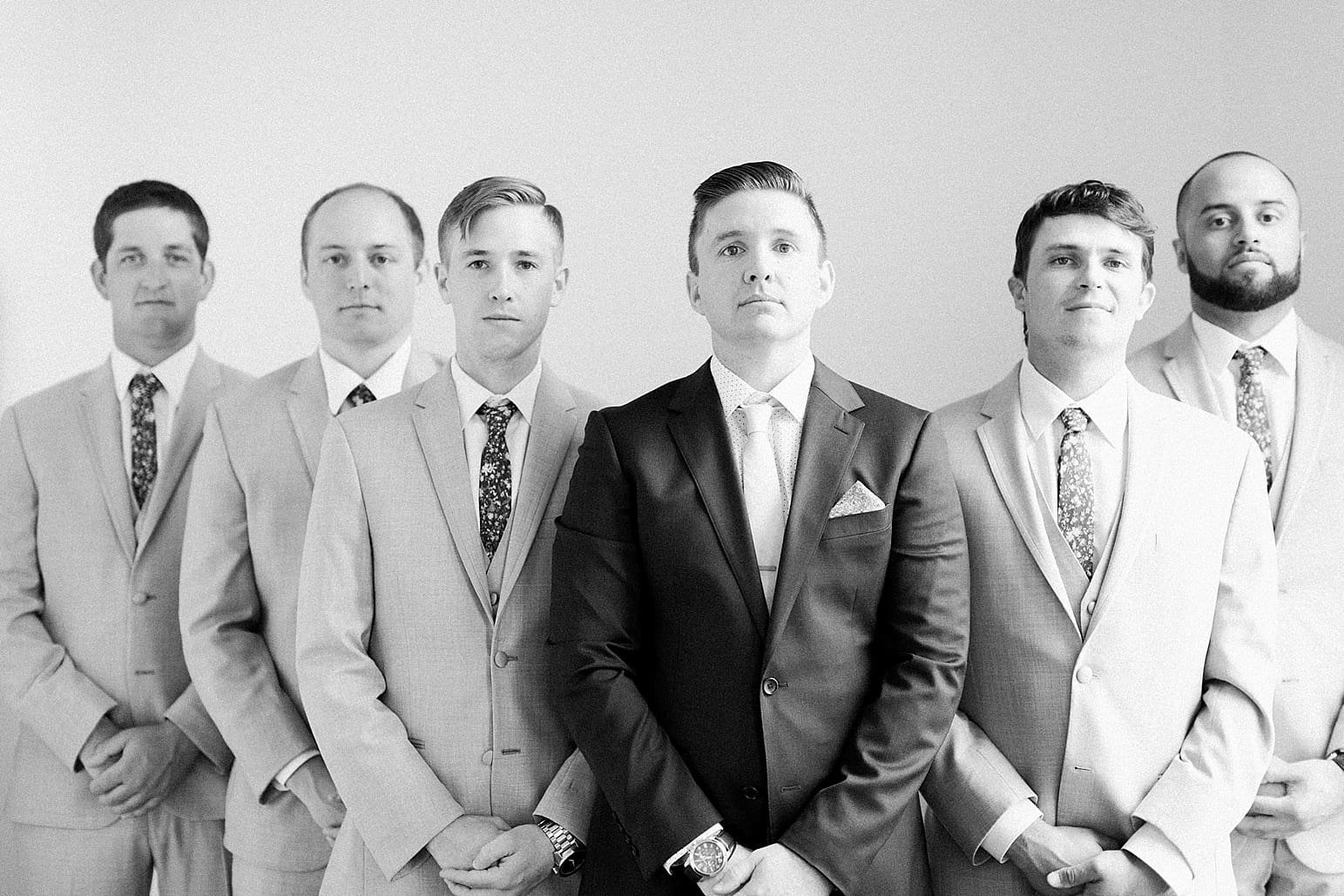 Arielle Peters Photography | Groom and groomsmen by white wall on wedding day at Loft 310 in Kalamazoo, Michigan.