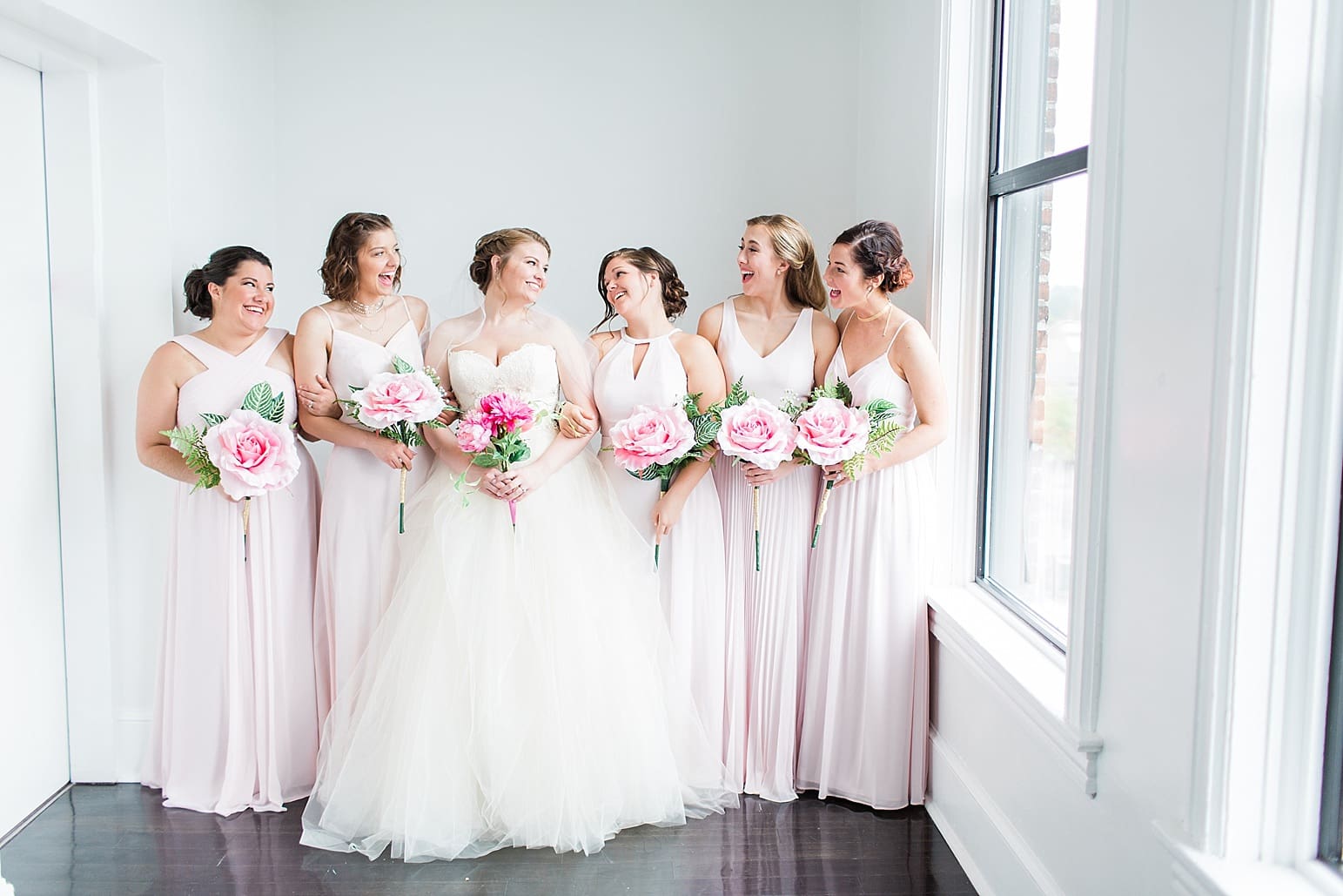 Arielle Peters Photography | Bride and bridesmaids next to large loft windows on wedding day at Loft 310 in Kalamazoo, Michigan.