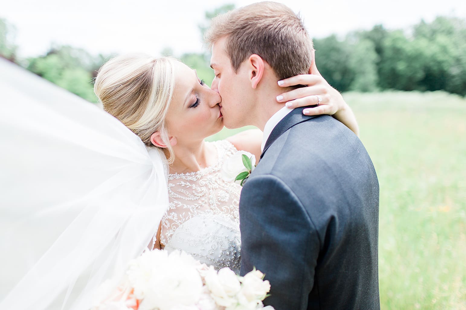Arielle Peters Photography | Bride and groom kissing in open field on wedding day at the Spohn Ballroom in Goshen, Indiana.