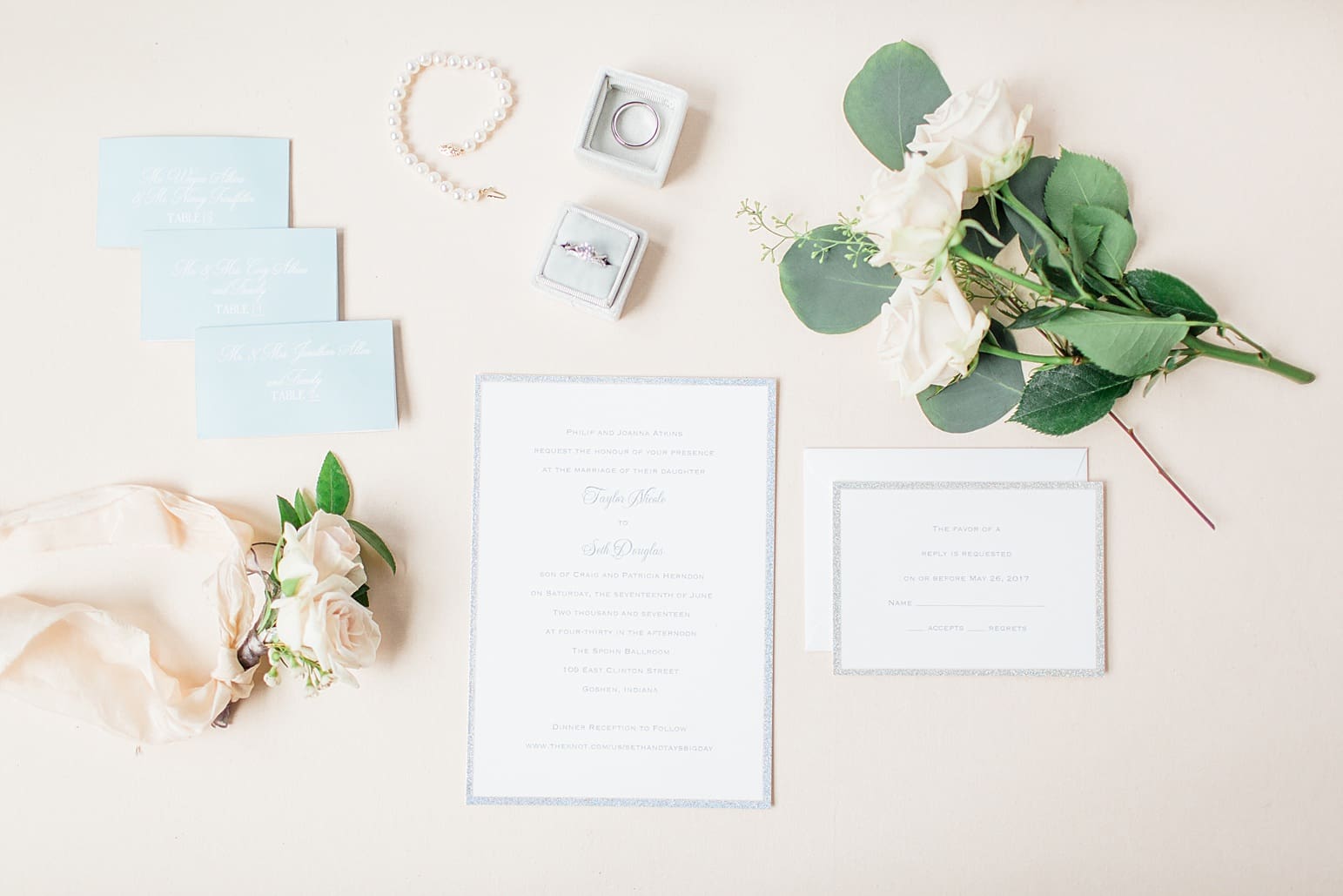 Arielle Peters Photography | Wedding invitation and jewelry on cream background on wedding day at the Spohn Ballroom in Goshen, Indiana.