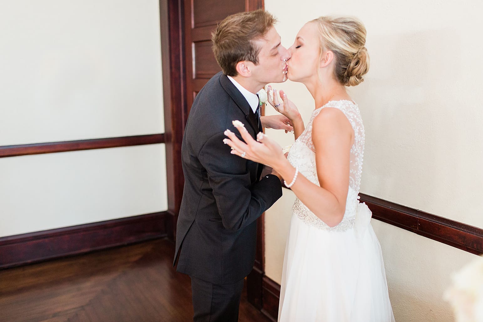 Arielle Peters Photography | Bride and groom kissing by wedding cake at wedding reception on wedding day at the Spohn Ballroom in Goshen, Indiana.