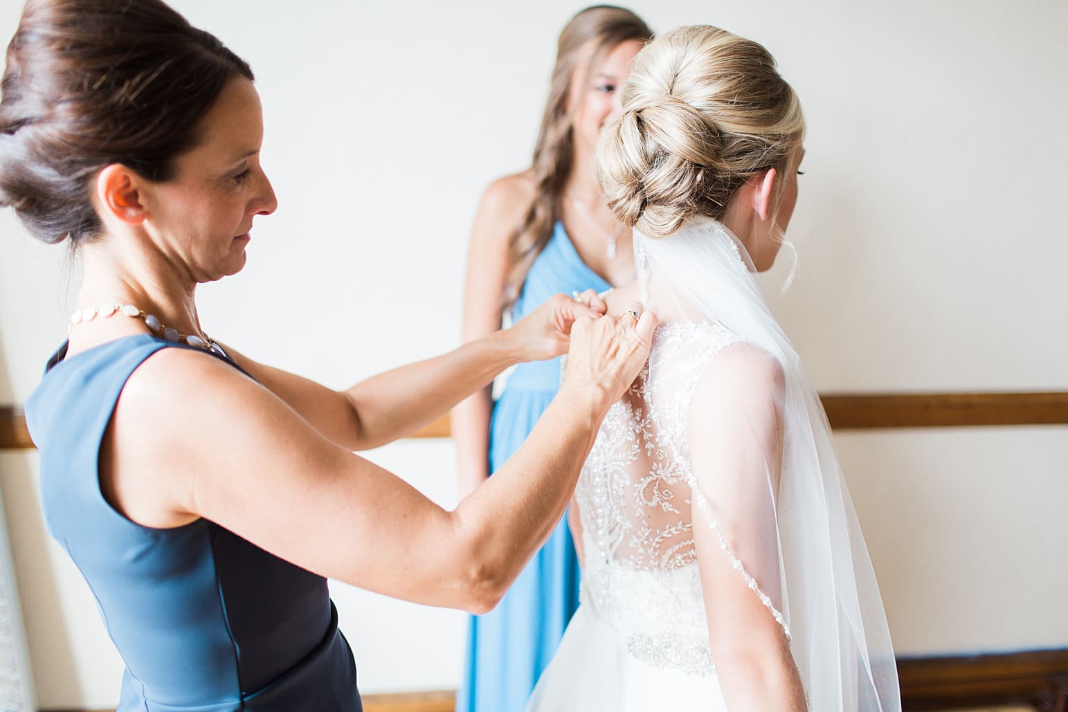 Arielle Peters Photography | Bridesmaids helping bride get ready on wedding day at the Spohn Ballroom in Goshen, Indiana.