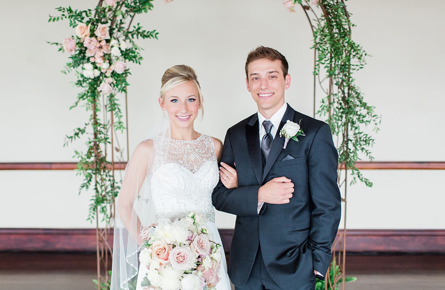 Arielle Peters Photography | Bride and groom under rose covered arch on wedding day at the Spohn Ballroom in Goshen, Indiana.