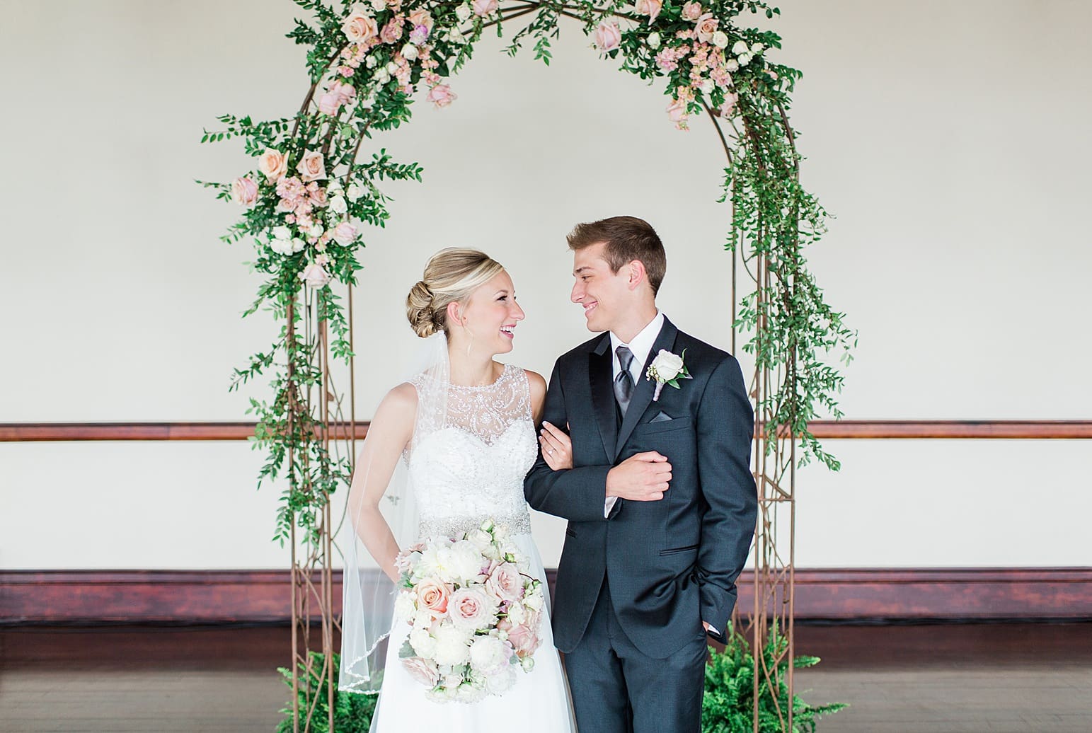 Arielle Peters Photography | Bride and groom under rose covered arch on wedding day at the Spohn Ballroom in Goshen, Indiana.