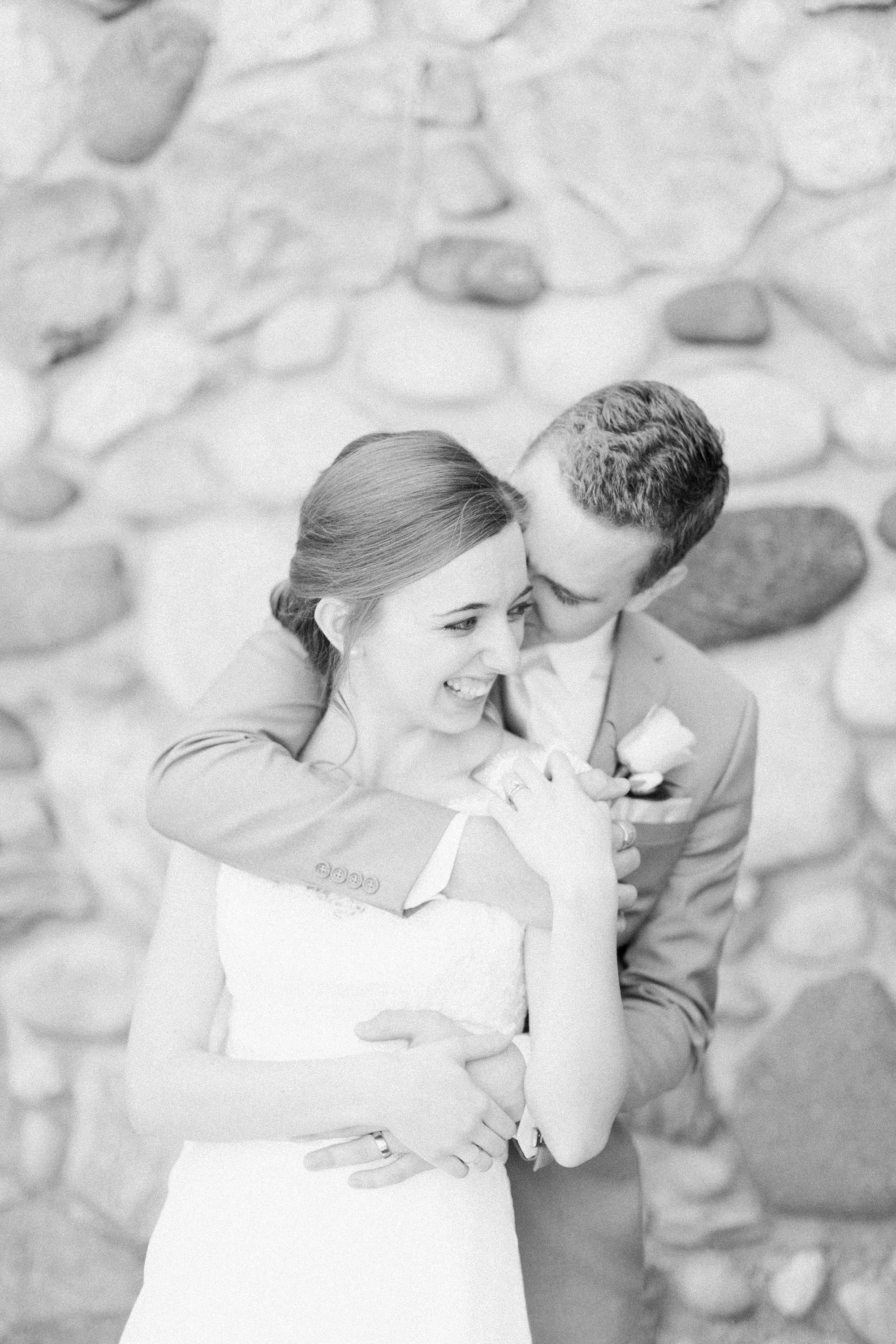 Arielle Peters Photography | Bride and groom laughing next to historic cobblestone building on wedding day at Lawton Lions Heritage Community Center in Lawton, Michigan.