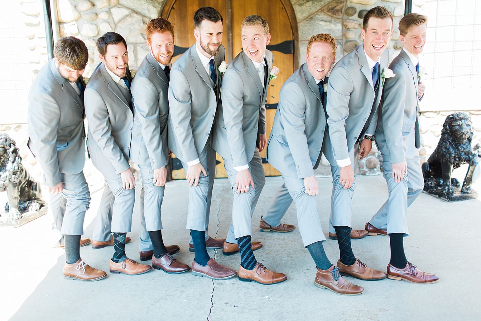 Arielle Peters Photography | Groom and groomsmen showing their socks in front of wooden cellar door on wedding day at Lawton Lions Heritage Community Center in Lawton, Michigan.