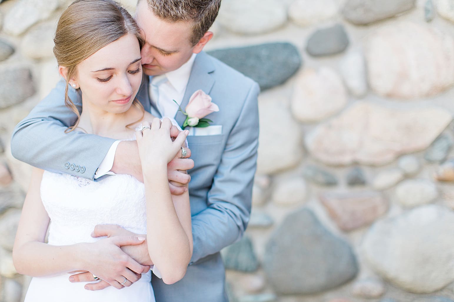Arielle Peters Photography | Groom holding bride next to historic cobblestone building on wedding day at Lawton Lions Heritage Community Center in Lawton, Michigan.