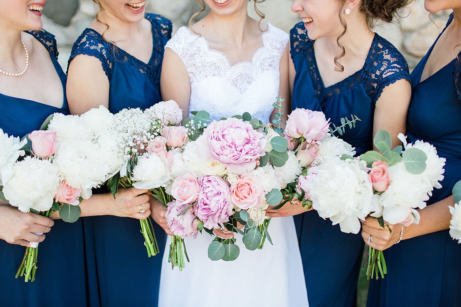 Arielle Peters Photography | Bride and bridesmaids bouquets next to historic cobblestone building on wedding day at Lawton Lions Heritage Community Center in Lawton, Michigan.