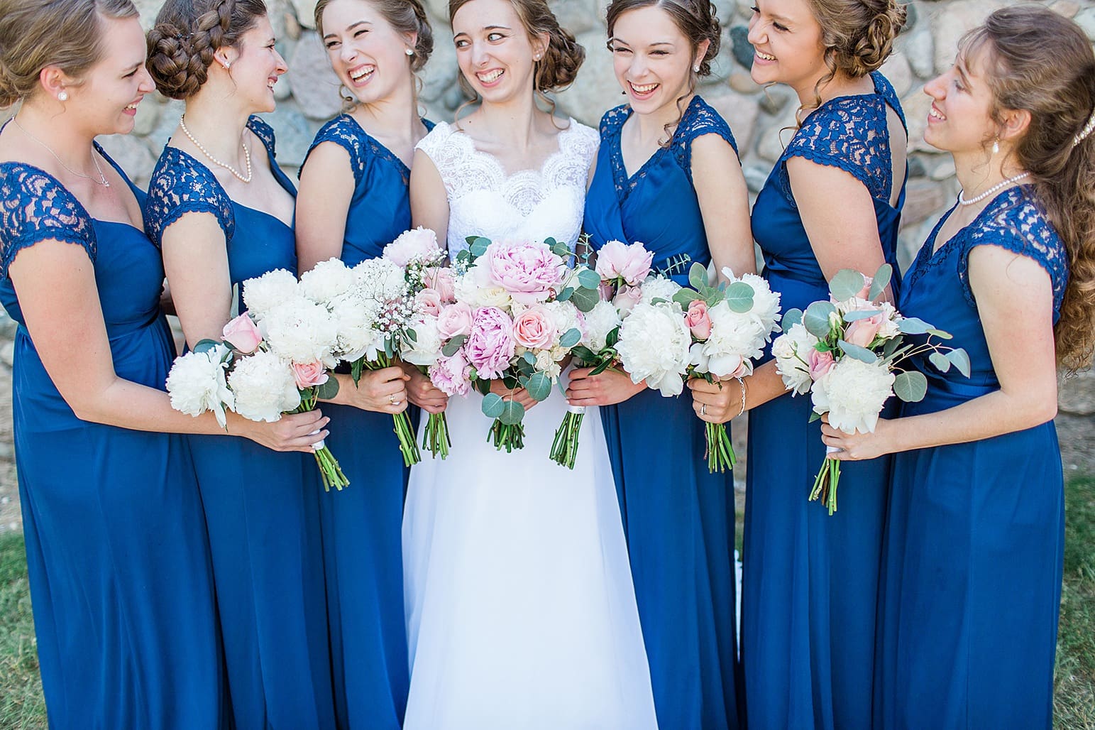 Arielle Peters Photography | Bride and bridesmaids laughing next to historic cobblestone building on wedding day at Lawton Lions Heritage Community Center in Lawton, Michigan.