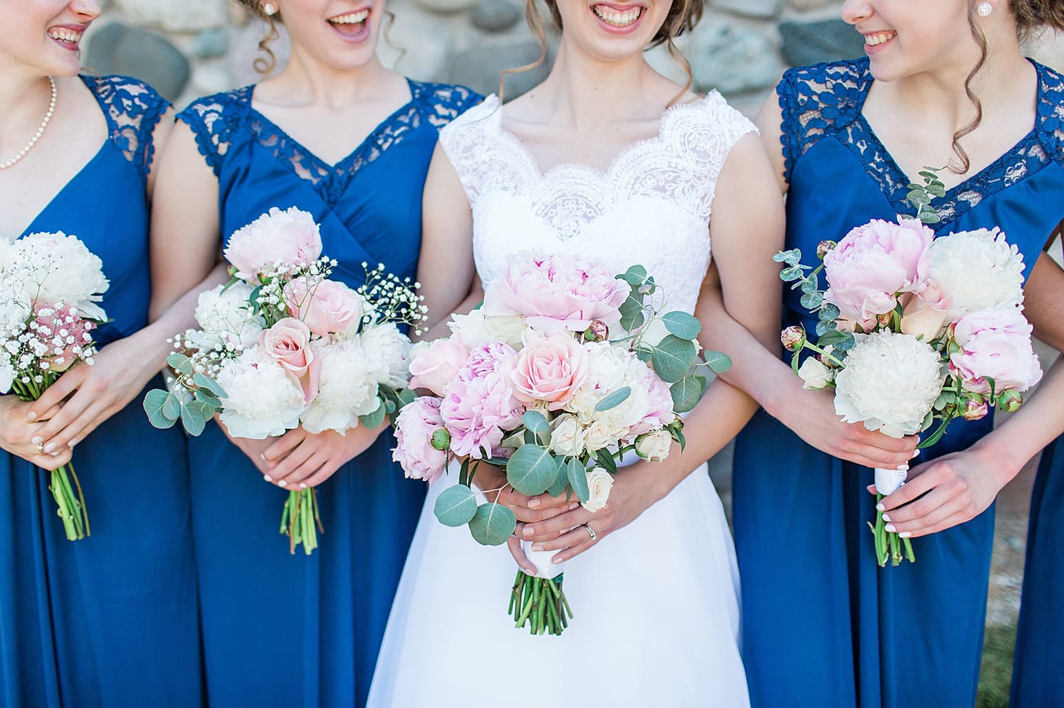 Arielle Peters Photography | Bride and bridesmaids holding bouquets next to historic cobblestone building on wedding day at Lawton Lions Heritage Community Center in Lawton, Michigan.