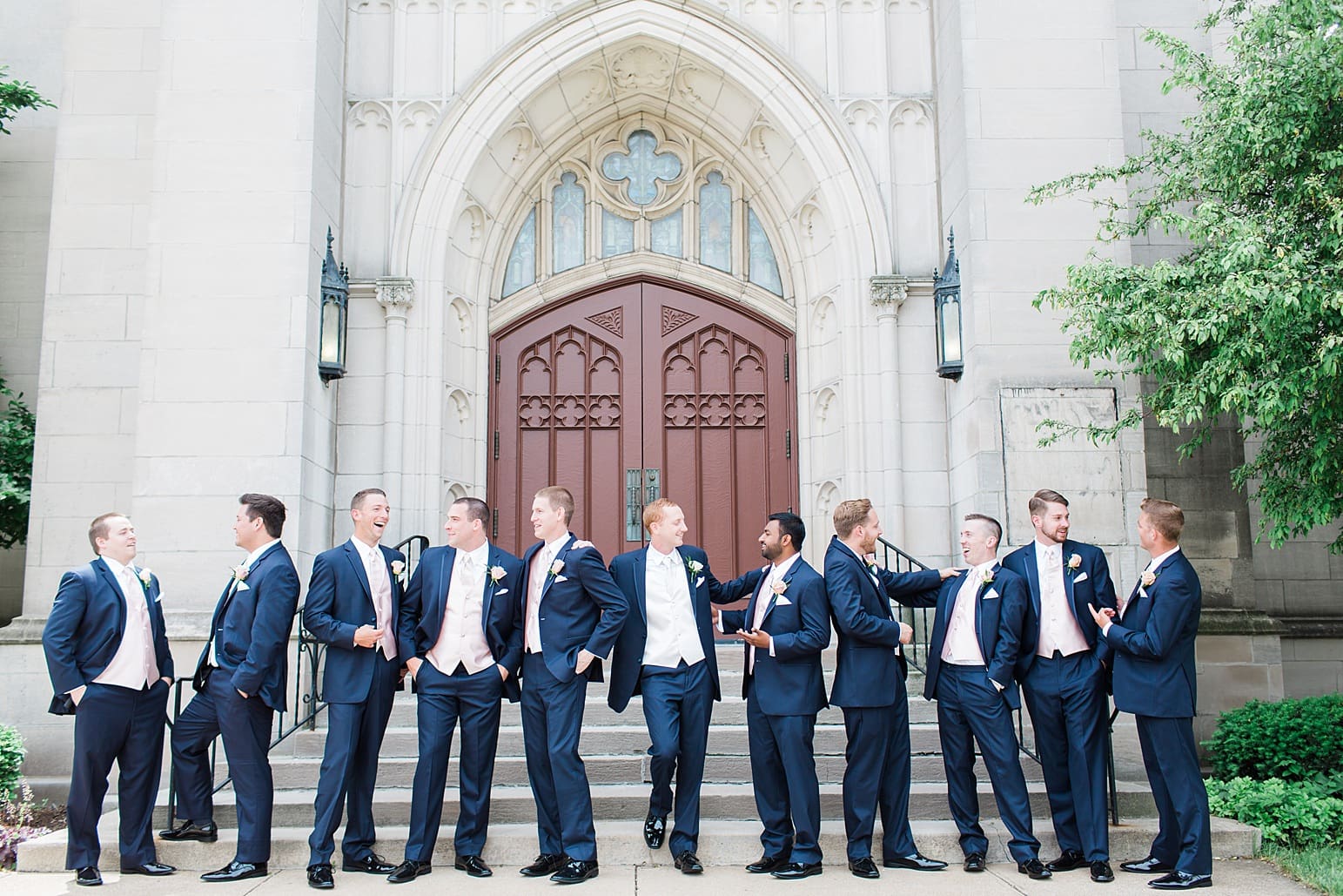 Arielle Peters Photography | Groom and groomsmen laughing outside large cathedral church on wedding day at First United Methodist Church in Mishawaka, Indiana.