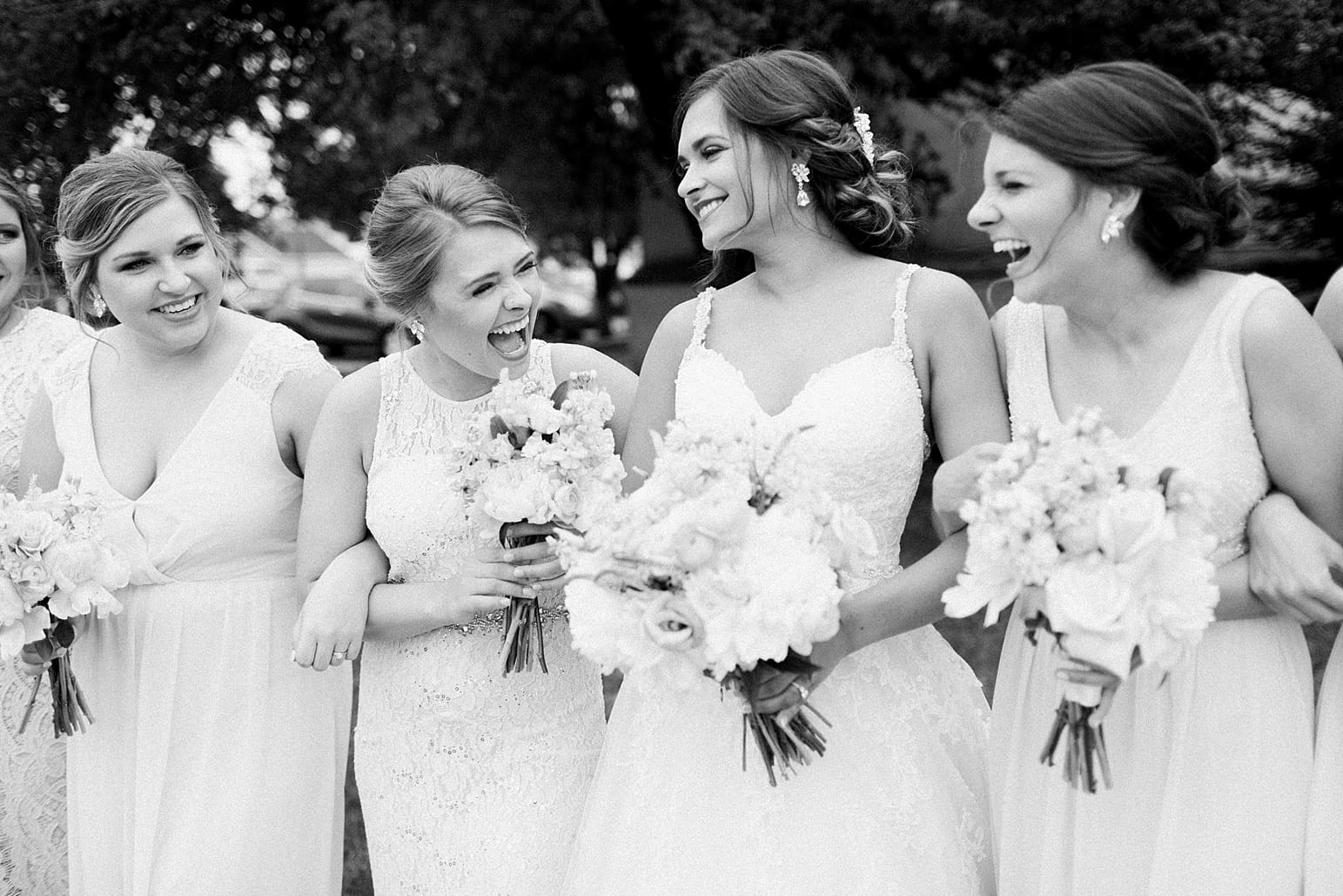 Arielle Peters Photography | Bride and bridesmaids linking arms outside large cathedral church on wedding day at First United Methodist Church in Mishawaka, Indiana.