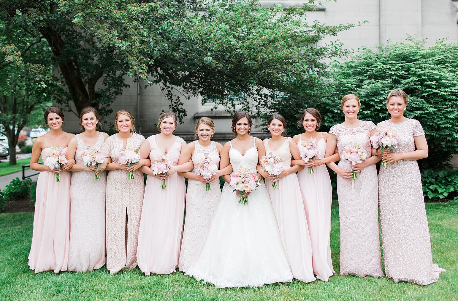 Arielle Peters Photography | Bride and bridesmaids under tree outside large cathedral church on wedding day at First United Methodist Church in Mishawaka, Indiana.