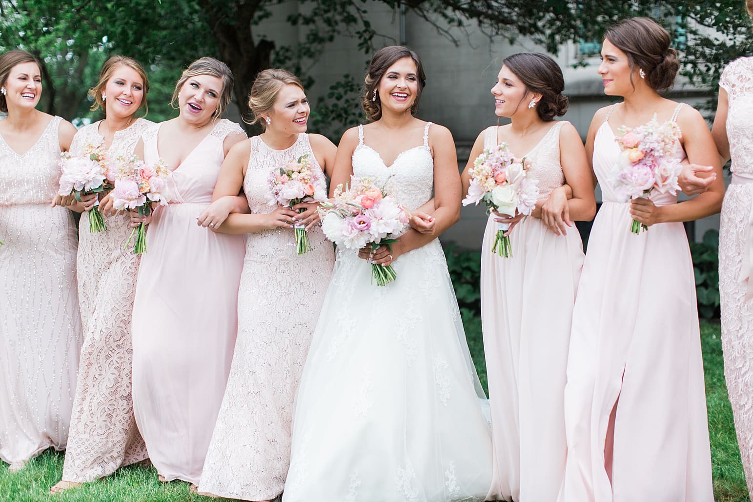 Arielle Peters Photography | Bride and bridesmaids under tree outside large cathedral church on wedding day at First United Methodist Church in Mishawaka, Indiana.