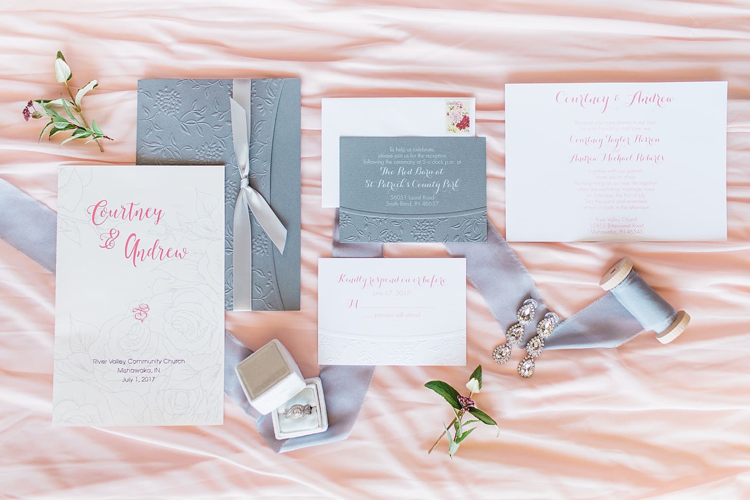 Arielle Peters Photography | Wedding invitations and jewelry on pink background on wedding day at St. Joseph County Parks in South Bend, Indiana.