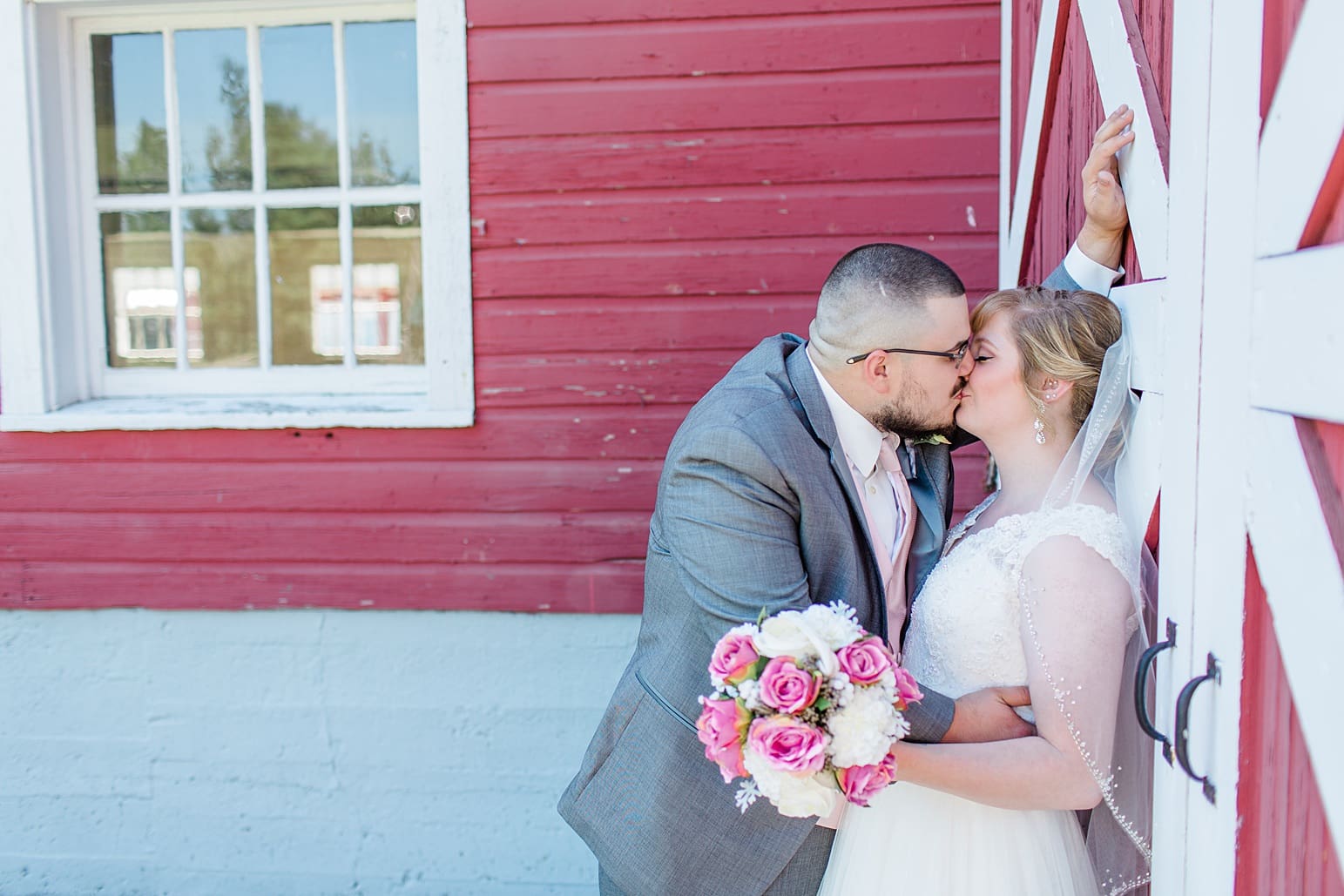 Arielle Peters Photography | Bride and groom kissing against old red barn on wedding day at St. Joseph County Parks in South Bend, Indiana.