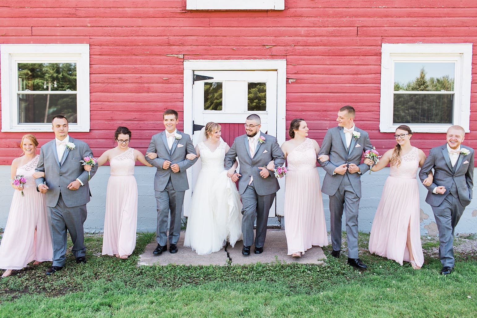 Arielle Peters Photography | Wedding party linked arms next to old red barn on wedding day at St. Joseph County Parks in South Bend, Indiana.