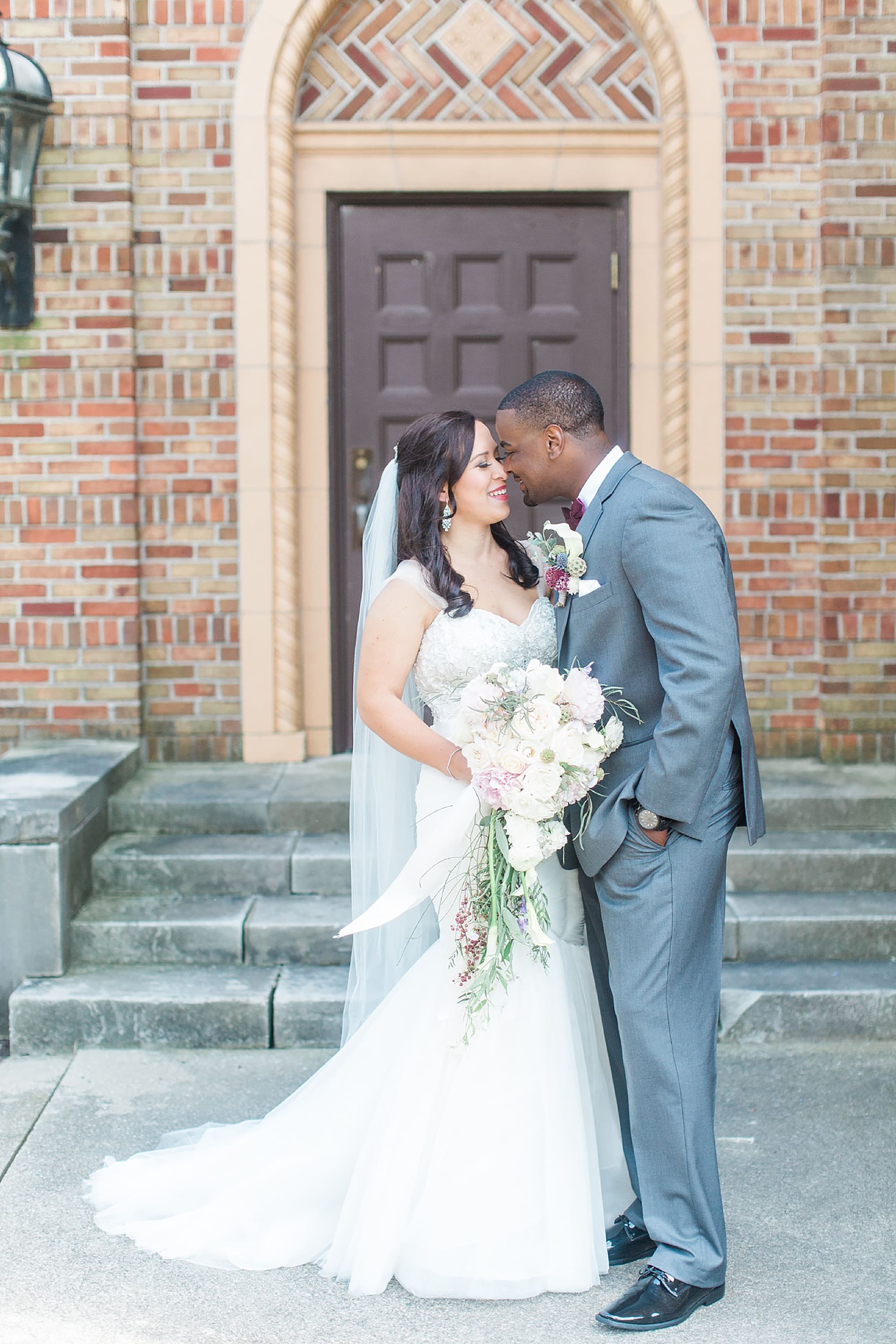Arielle Peters Photography | Bride and groom kissing in brick archway on wedding day photos at Nazareth Hall in Grand Rapids, Ohio. 