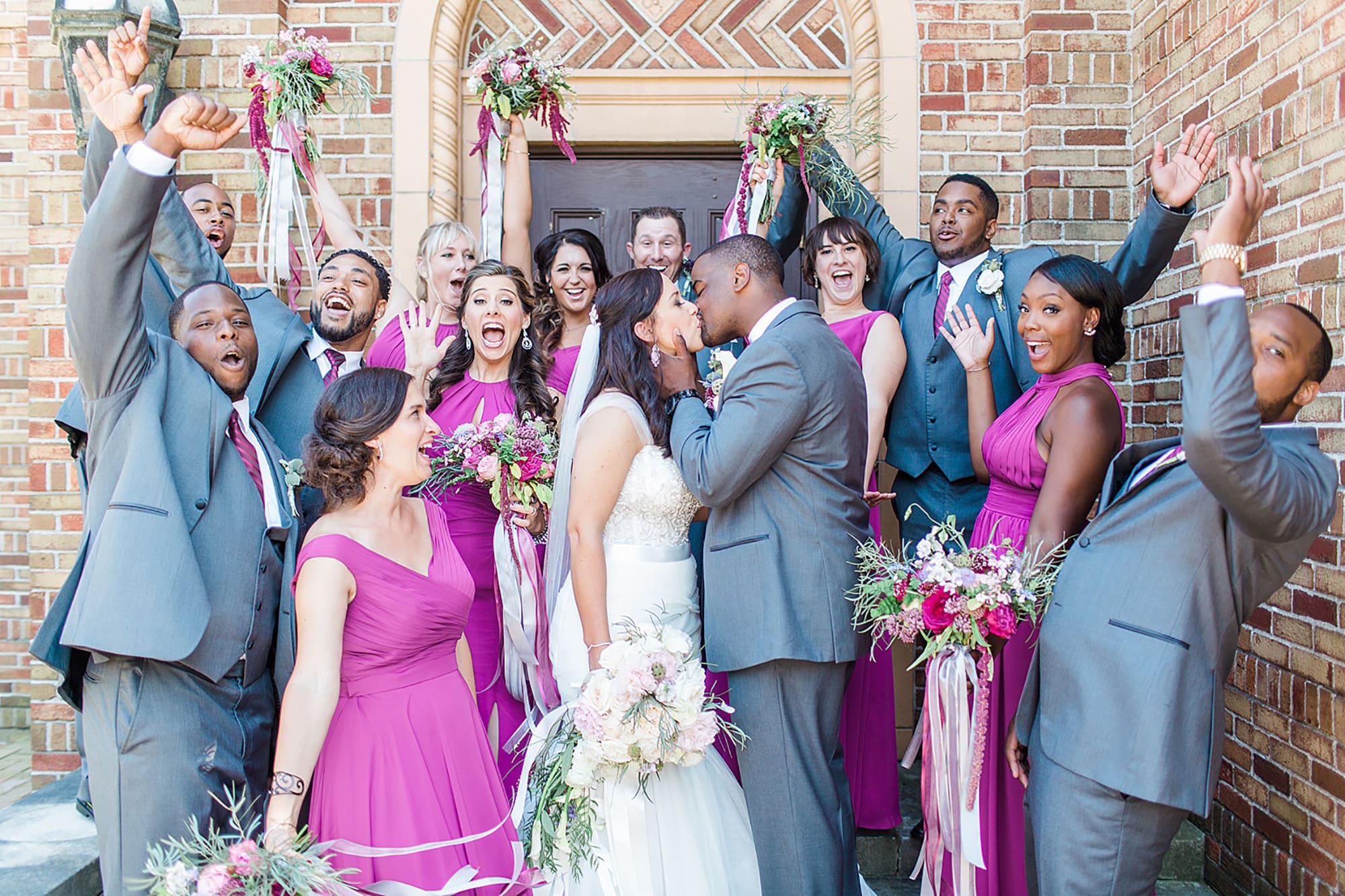 Arielle Peters Photography | Wedding party cheering next to brick building on wedding day photos at Nazareth Hall in Grand Rapids, Ohio. 