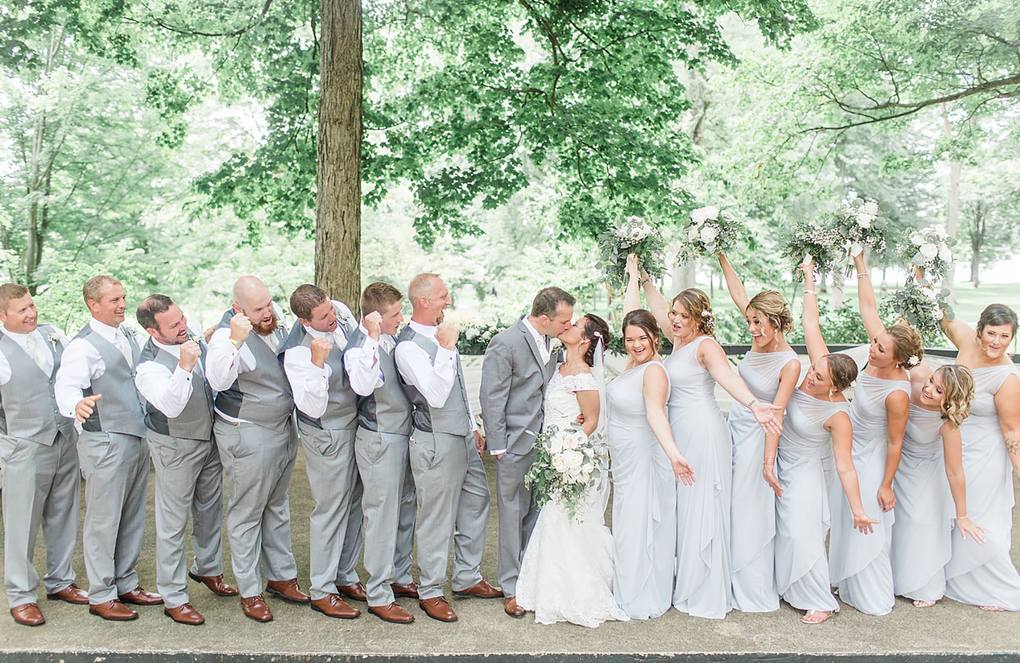 Arielle Peters Photography | Wedding party cheering in park on wedding day at Winona Heritage Room in Winona Lake, Indiana.