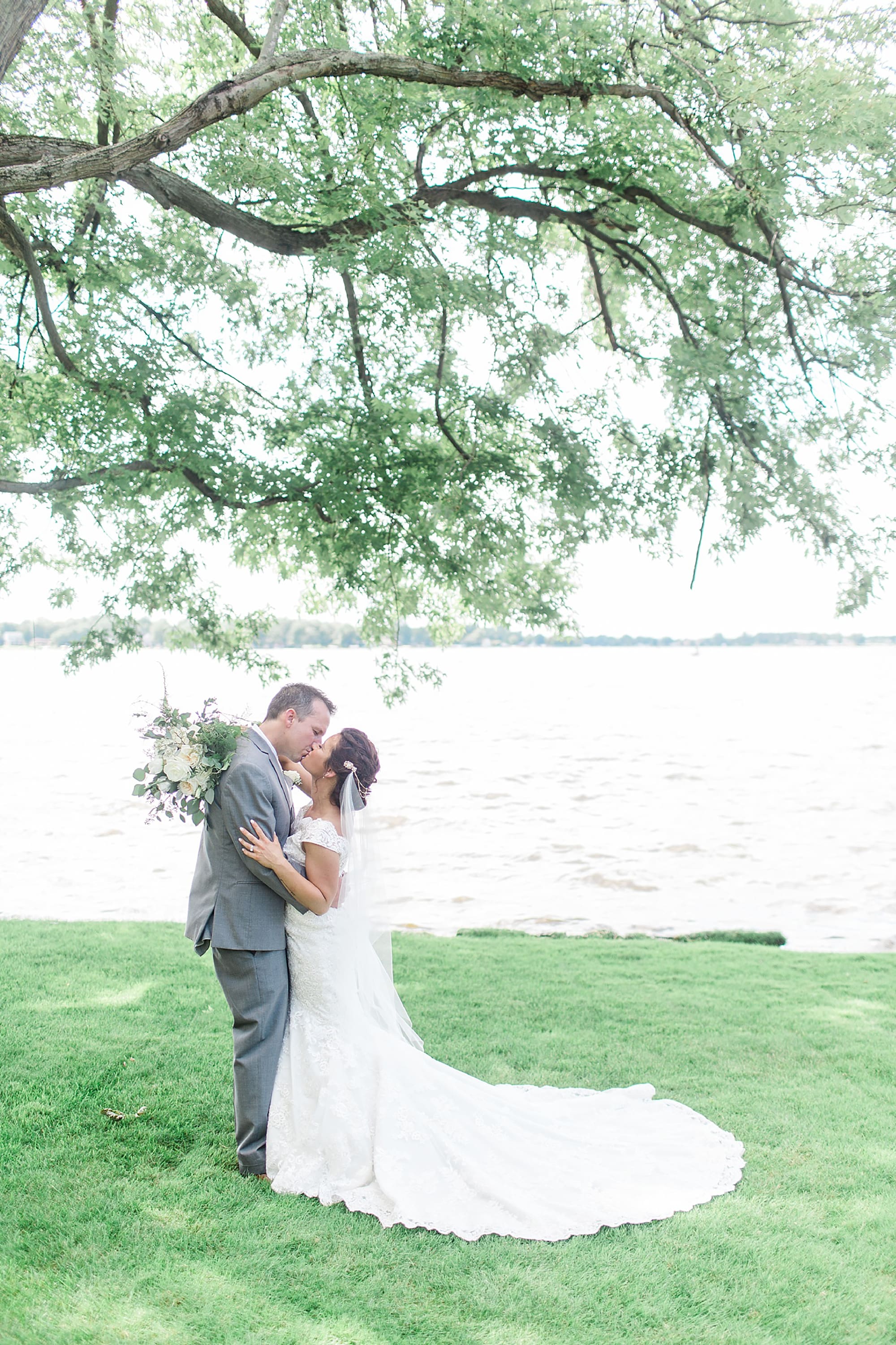 Arielle Peters Photography | Bride and groom kissing by lake on wedding day at Winona Heritage Room in Winona Lake, Indiana.