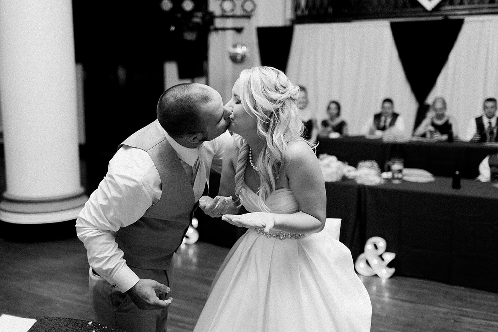 Arielle Peters Photography | Bride and groom kissing by the cake at wedding reception on wedding day at the Freemasons Hall in Fort Wayne, Indiana.