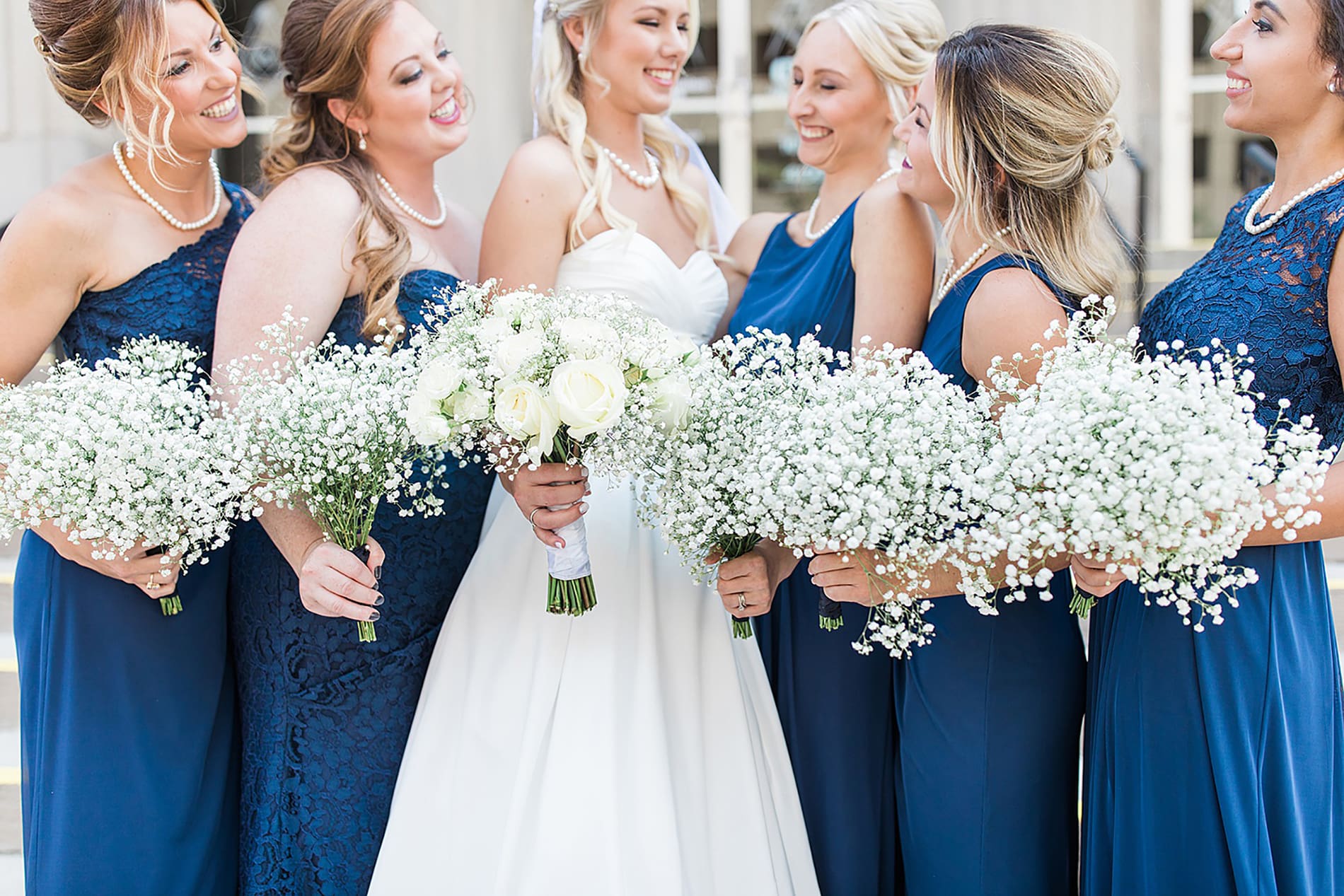 Arielle Peters Photography | Bride and bridesmaids holding bouquets outside church steps on wedding day at the Freemasons Hall in Fort Wayne, Indiana.