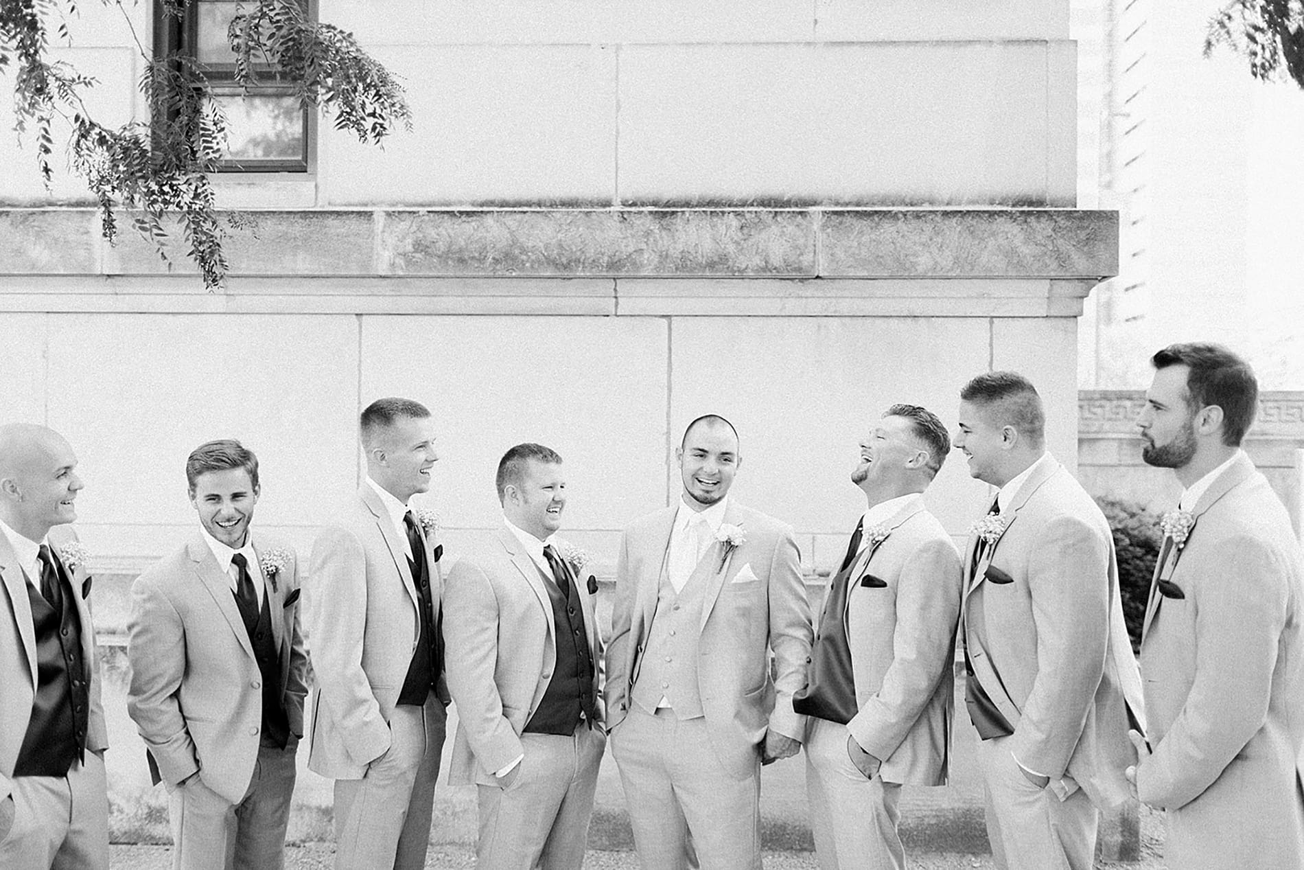 Arielle Peters Photography | Groom and groomsmen laughing next to church on wedding day at the Freemasons Hall in Fort Wayne, Indiana.