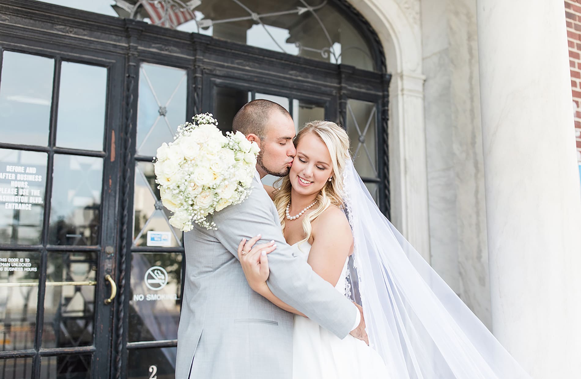 Arielle Peters Photography | Bride and groom kissing next to glass doors on wedding day at the Freemasons Hall in Fort Wayne, Indiana.