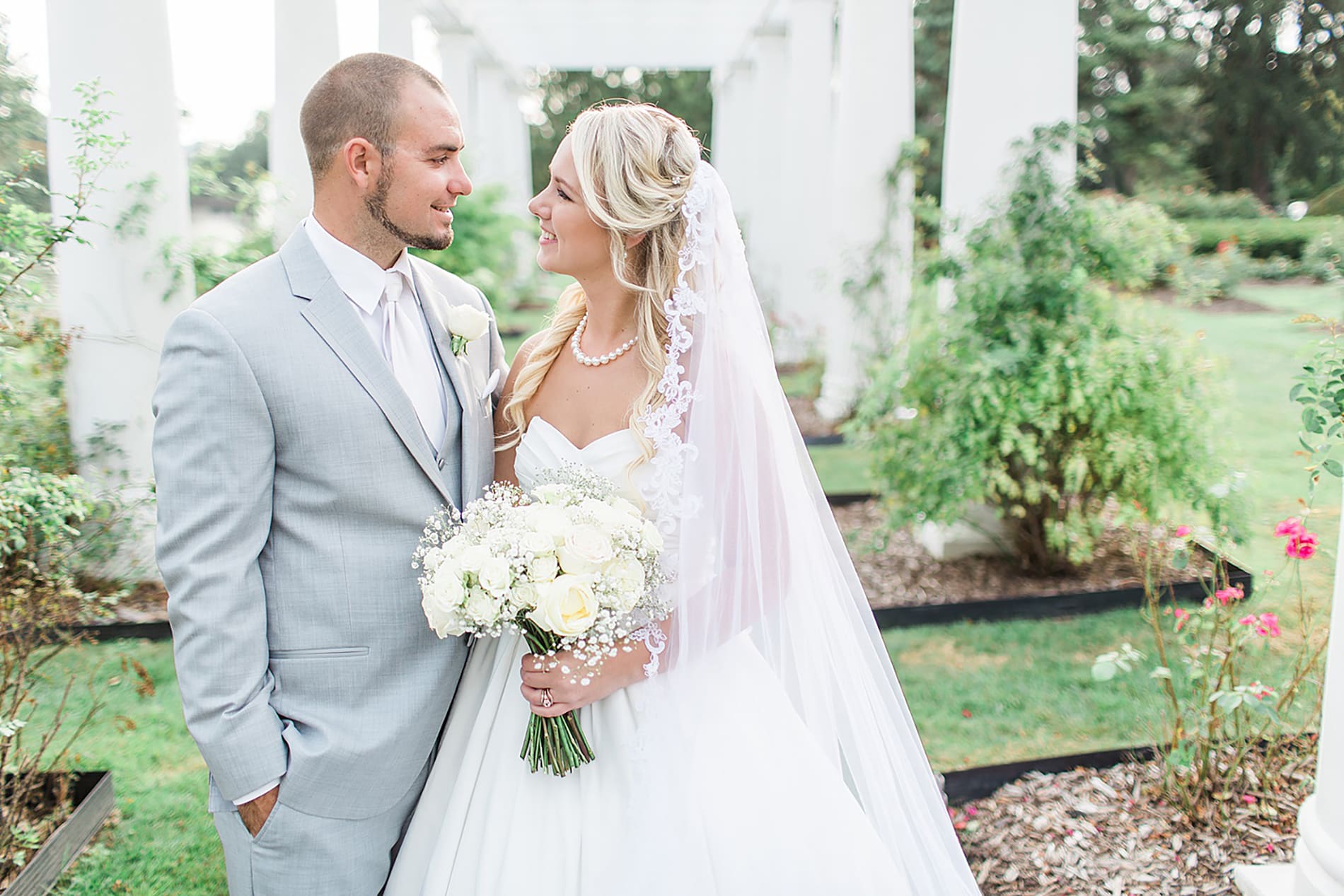 Arielle Peters Photography | Bride and groom smiling at each other in overgrown rose garden on wedding day at the Freemasons Hall in Fort Wayne, Indiana.