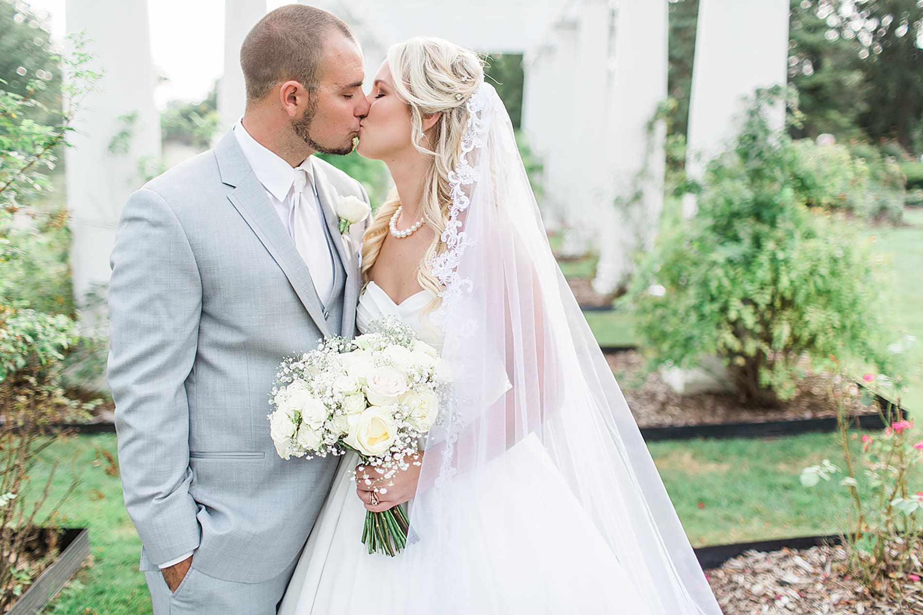 Arielle Peters Photography | Bride and groom kissing in overgrown rose garden on wedding day at the Freemasons Hall in Fort Wayne, Indiana.