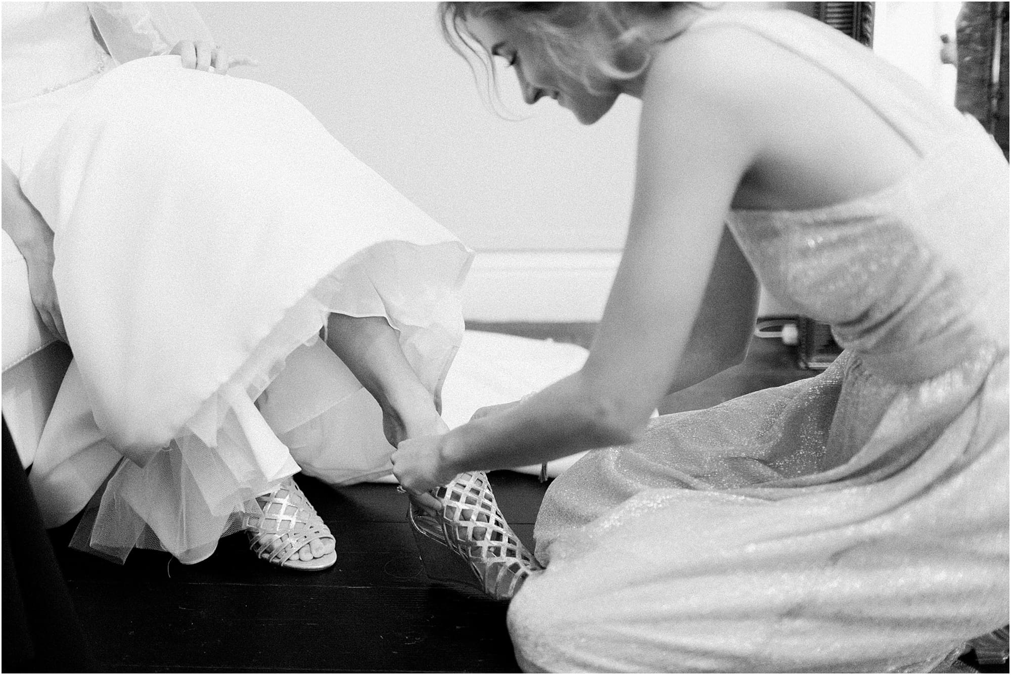 Arielle Peters Photography | Bridesmaid helping bride put on her shoes on wedding day at the Uptown Center in Michigan City, Indiana.