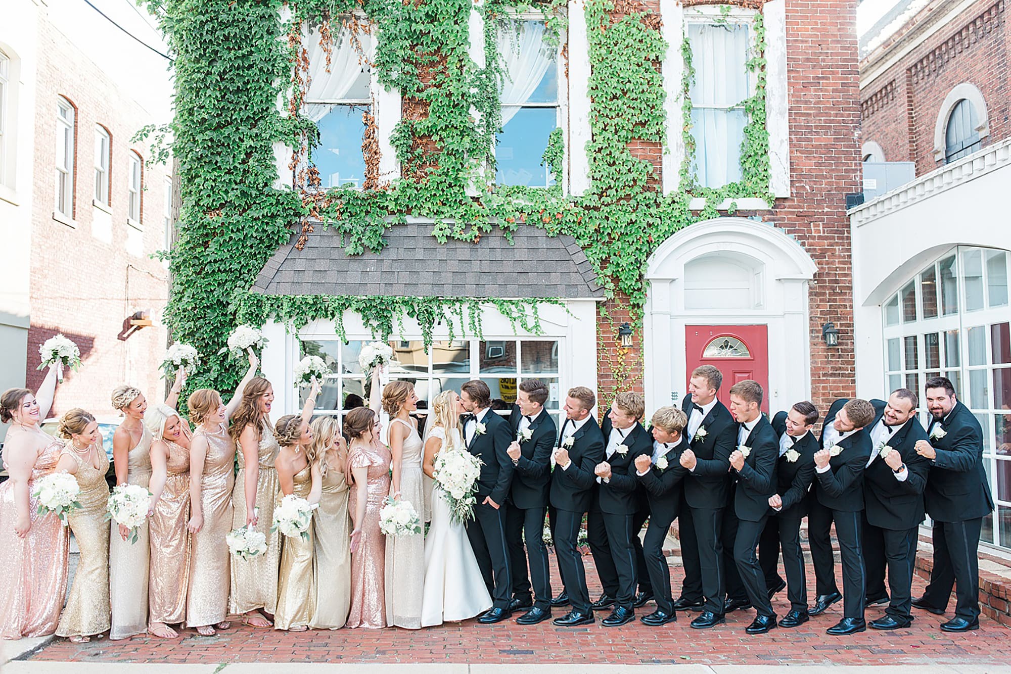 Arielle Peters Photography | Wedding party cheering next to ivy-covered building on wedding day at the Uptown Center in Michigan City, Indiana.