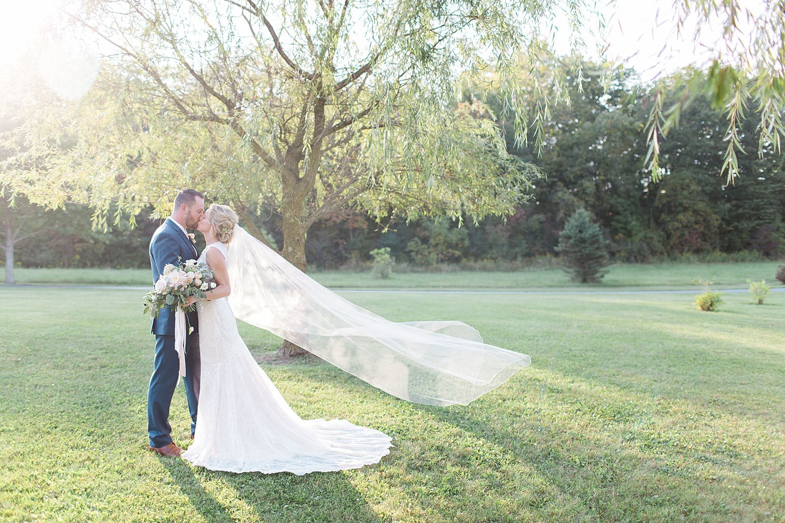 Arielle Peters Photography | Bride and groom kissing in open field next to pond on wedding day at Joseph Decuis Farm in Roanoke, Indiana.