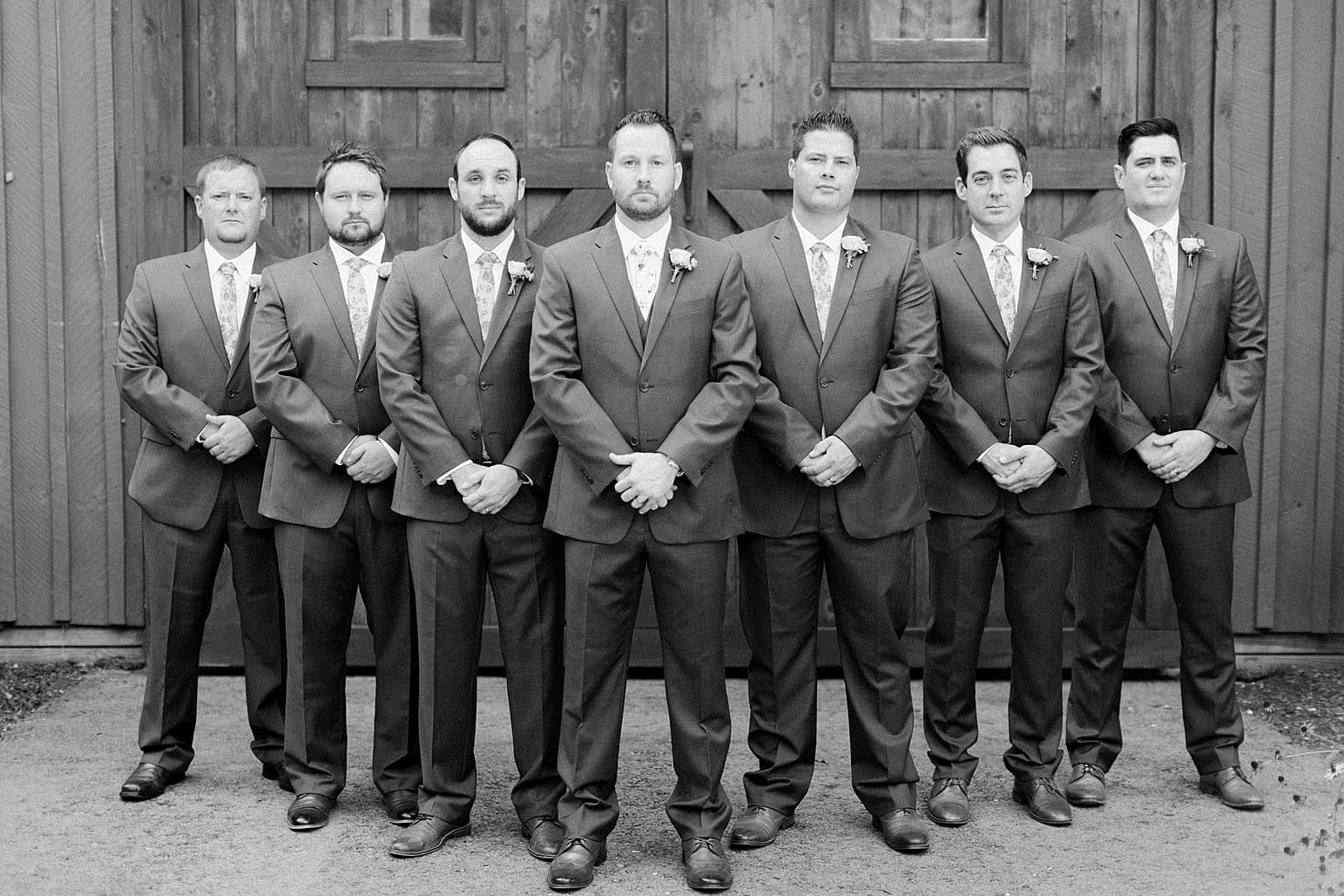Arielle Peters Photography | Groom and groomsmen standing in front of wood barn doors on wedding day at Joseph Decuis Farm in Roanoke, Indiana.