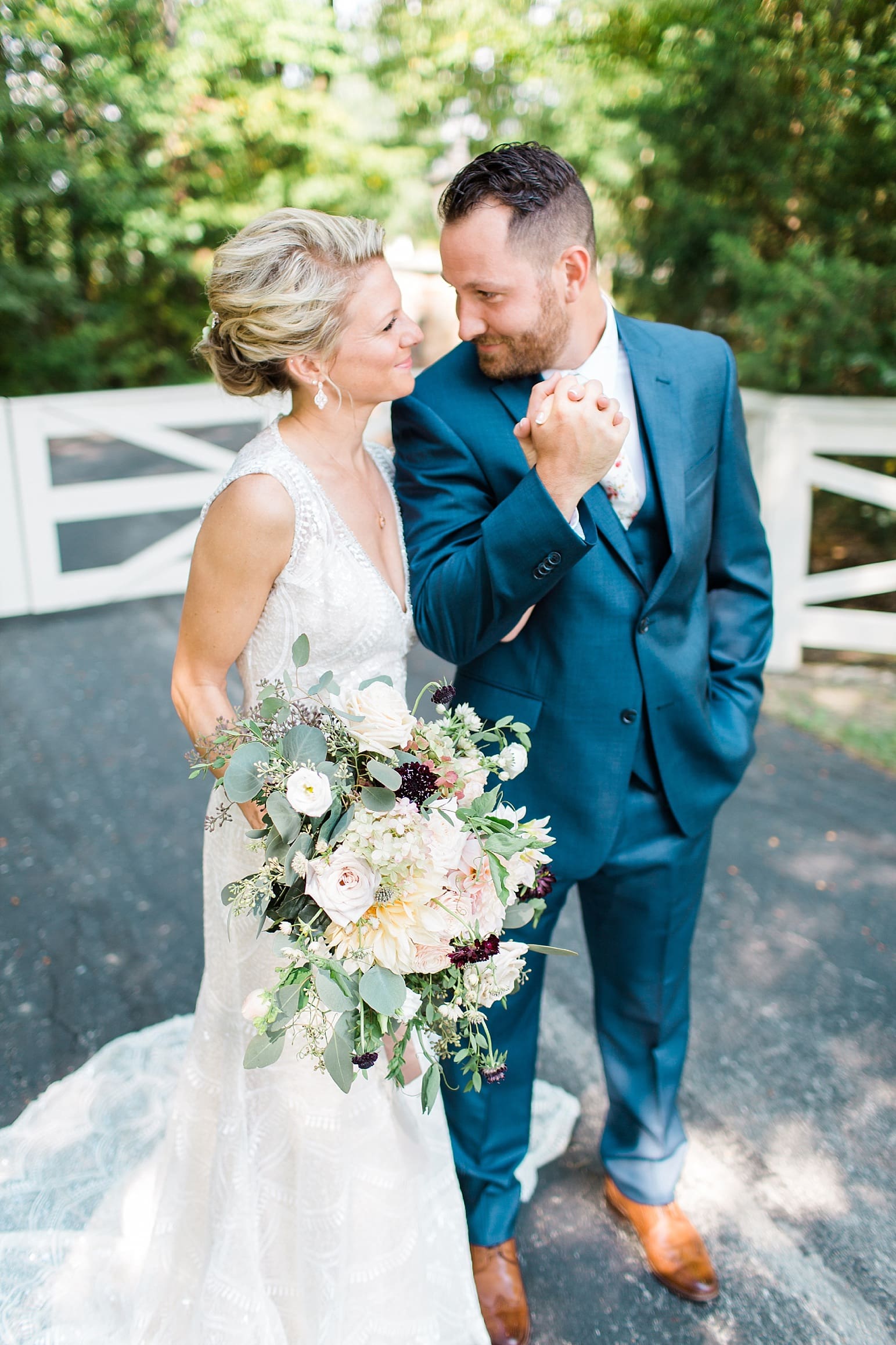 Arielle Peters Photography | Bride and groom holding hands next to white fence on wedding day at Joseph Decuis Farm in Roanoke, Indiana.
