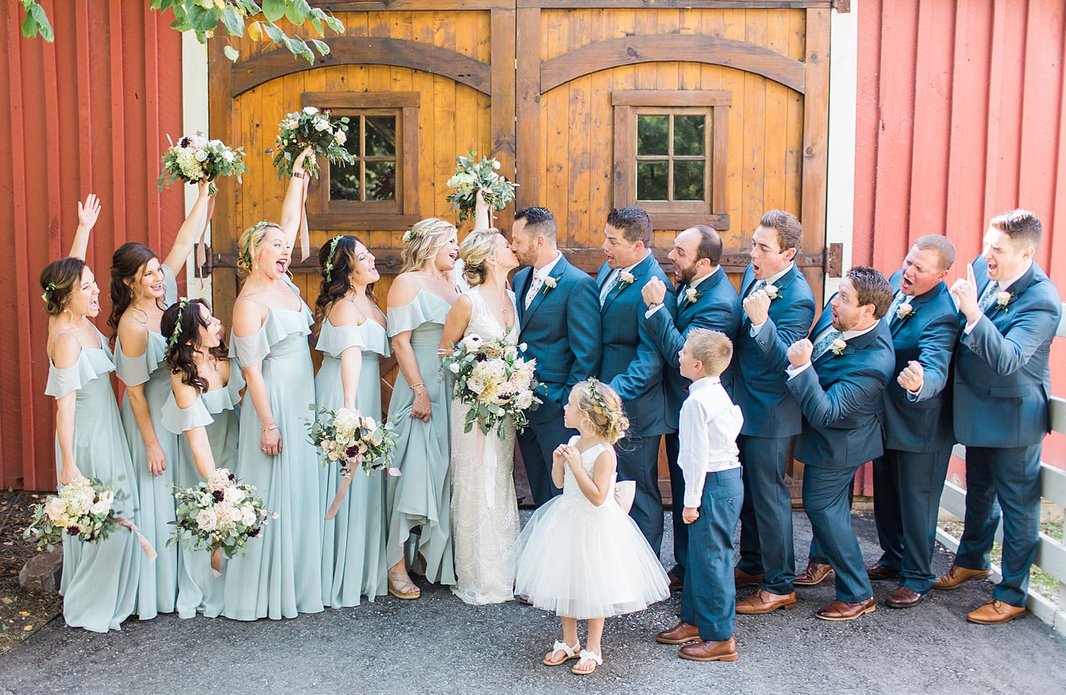 Arielle Peters Photography | Wedding party cheering in front of wooden barn door on wedding day at Joseph Decuis Farm in Roanoke, Indiana.