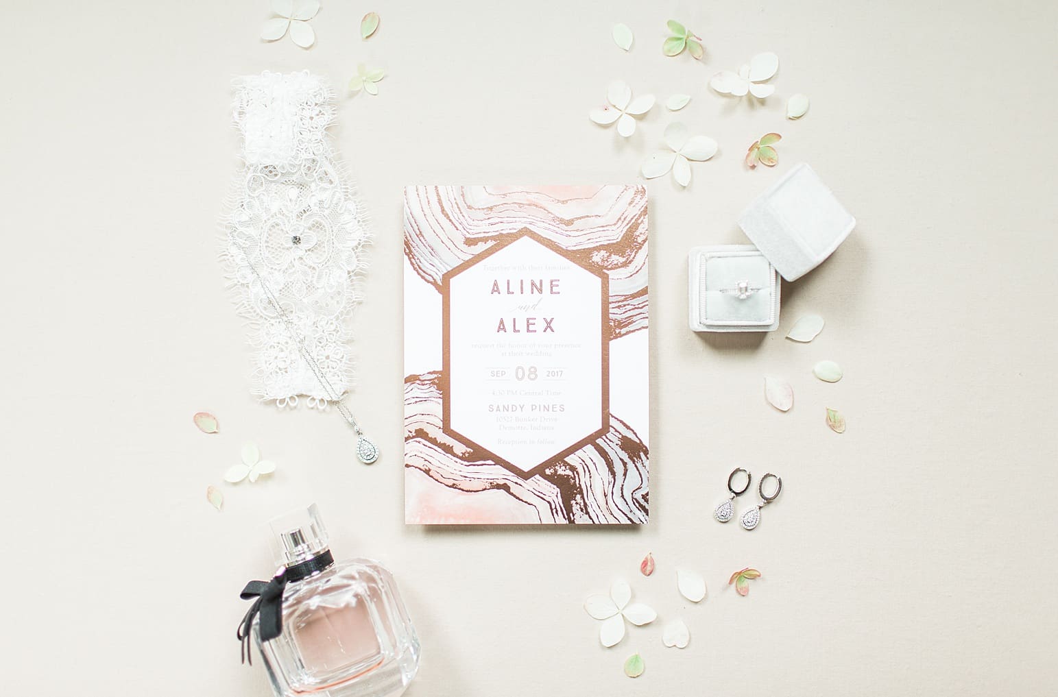 Arielle Peters Photography | Wedding invitation and perfume on cream background on wedding day at The Pavilion at Sandy Pines in Demotte, Indiana.