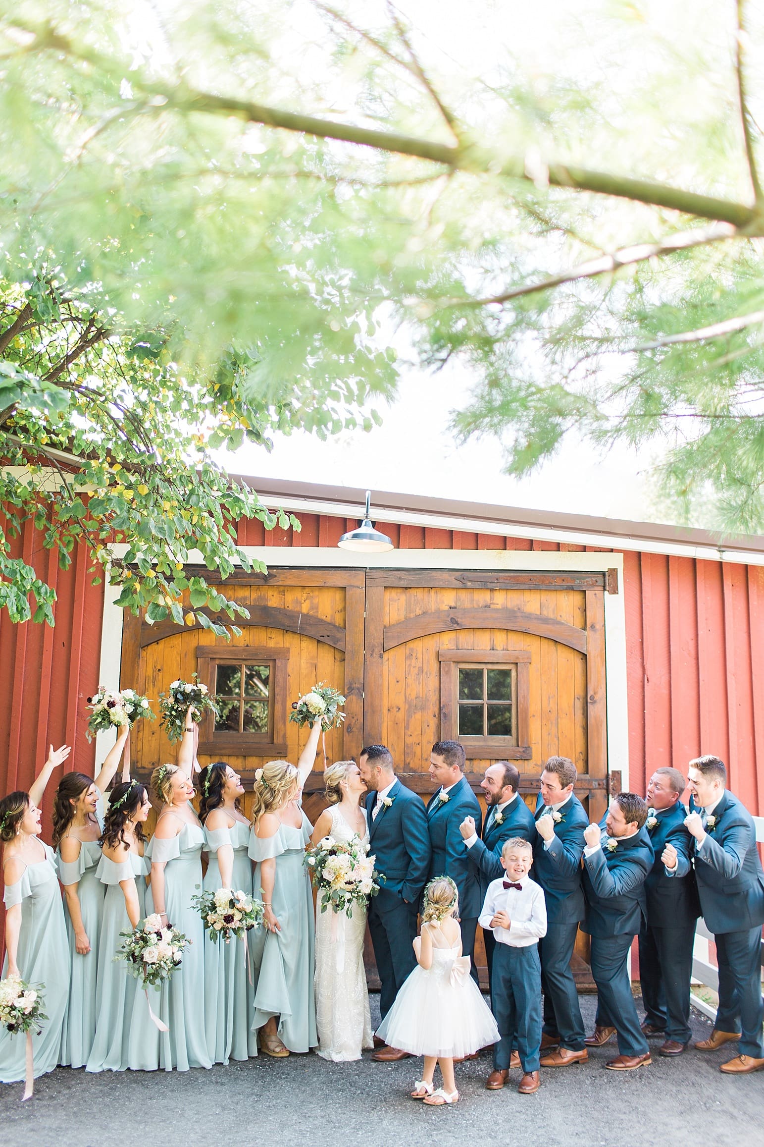 Arielle Peters Photography | Wedding party cheering in front of wooden barn door on wedding day at Joseph Decuis Farm in Roanoke, Indiana.