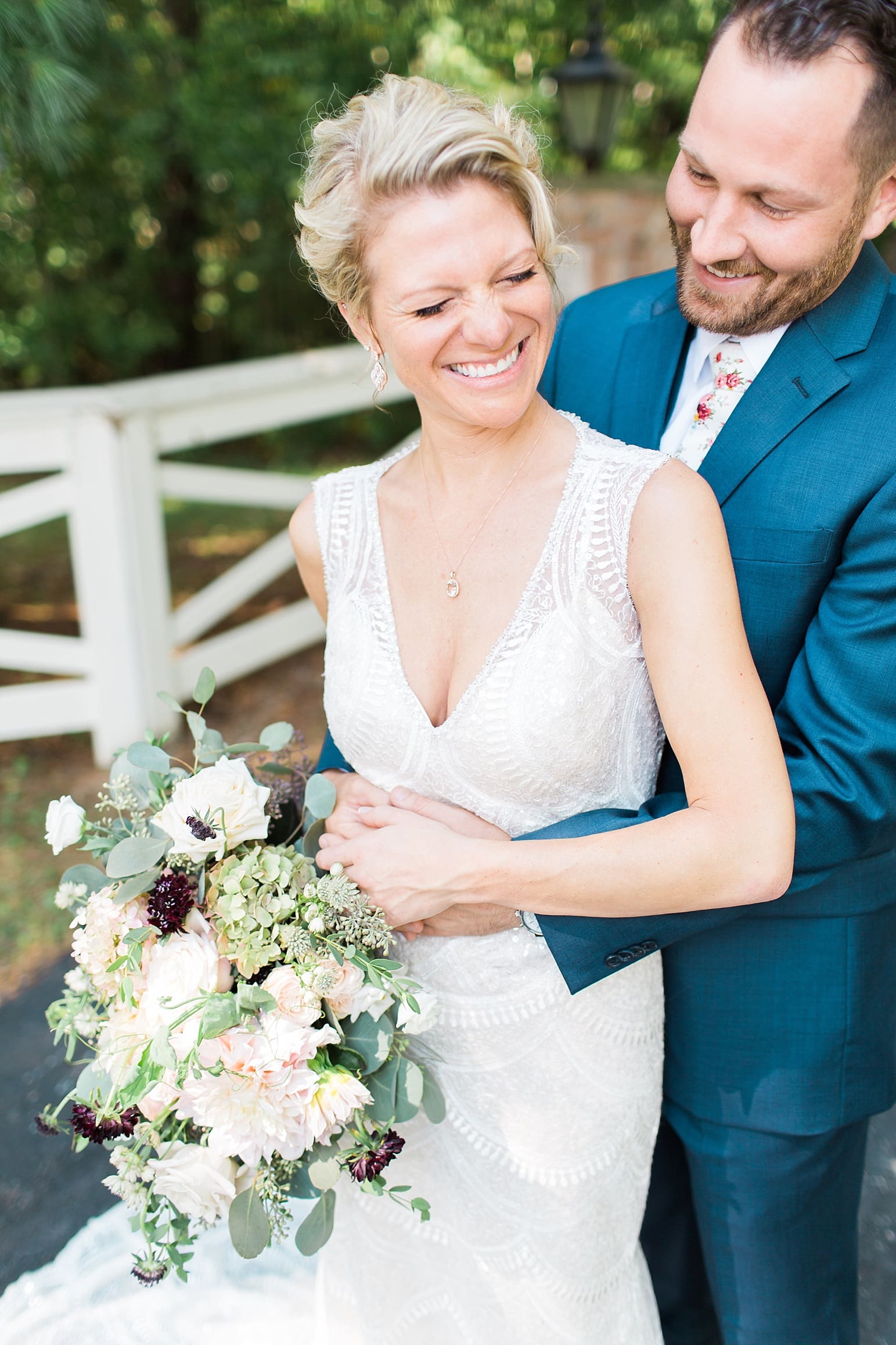 Arielle Peters Photography | Bride and groom laughing in front of white fence on wedding day at Joseph Decuis Farm in Roanoke, Indiana.