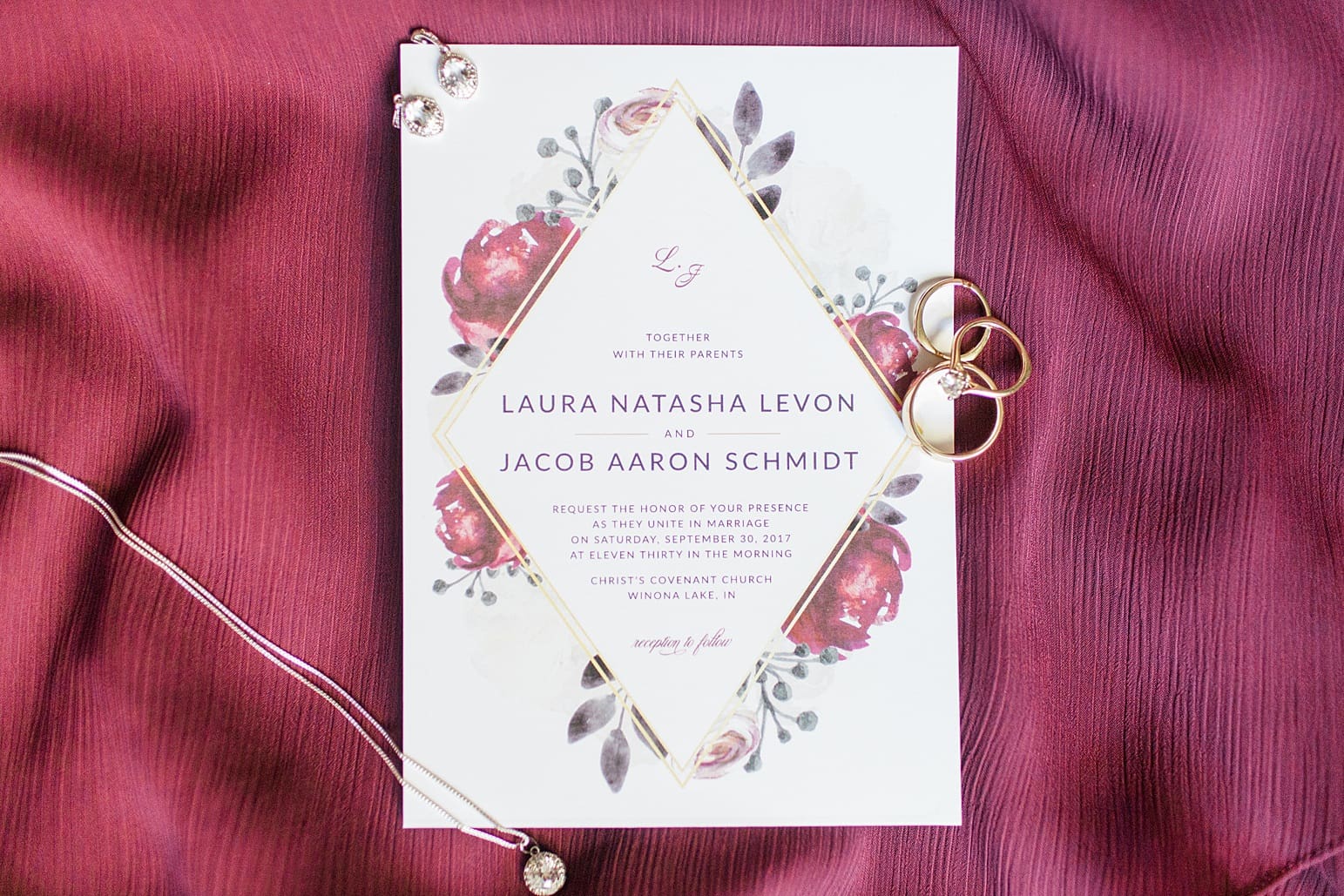 Arielle Peters Photography | Wedding invitations and jewelry on bright red background on fall wedding day in Winona Lake, Indiana.