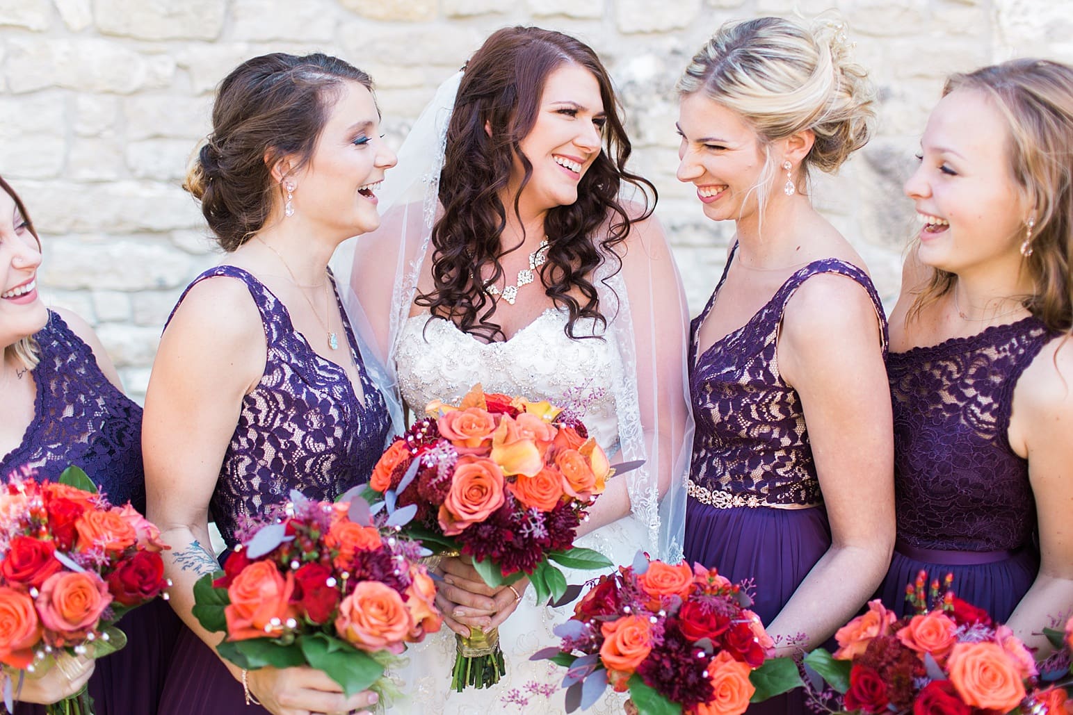 Arielle Peters Photography | Bride and bridesmaids next to limestone wall on wedding day in Carmel, Indiana. 