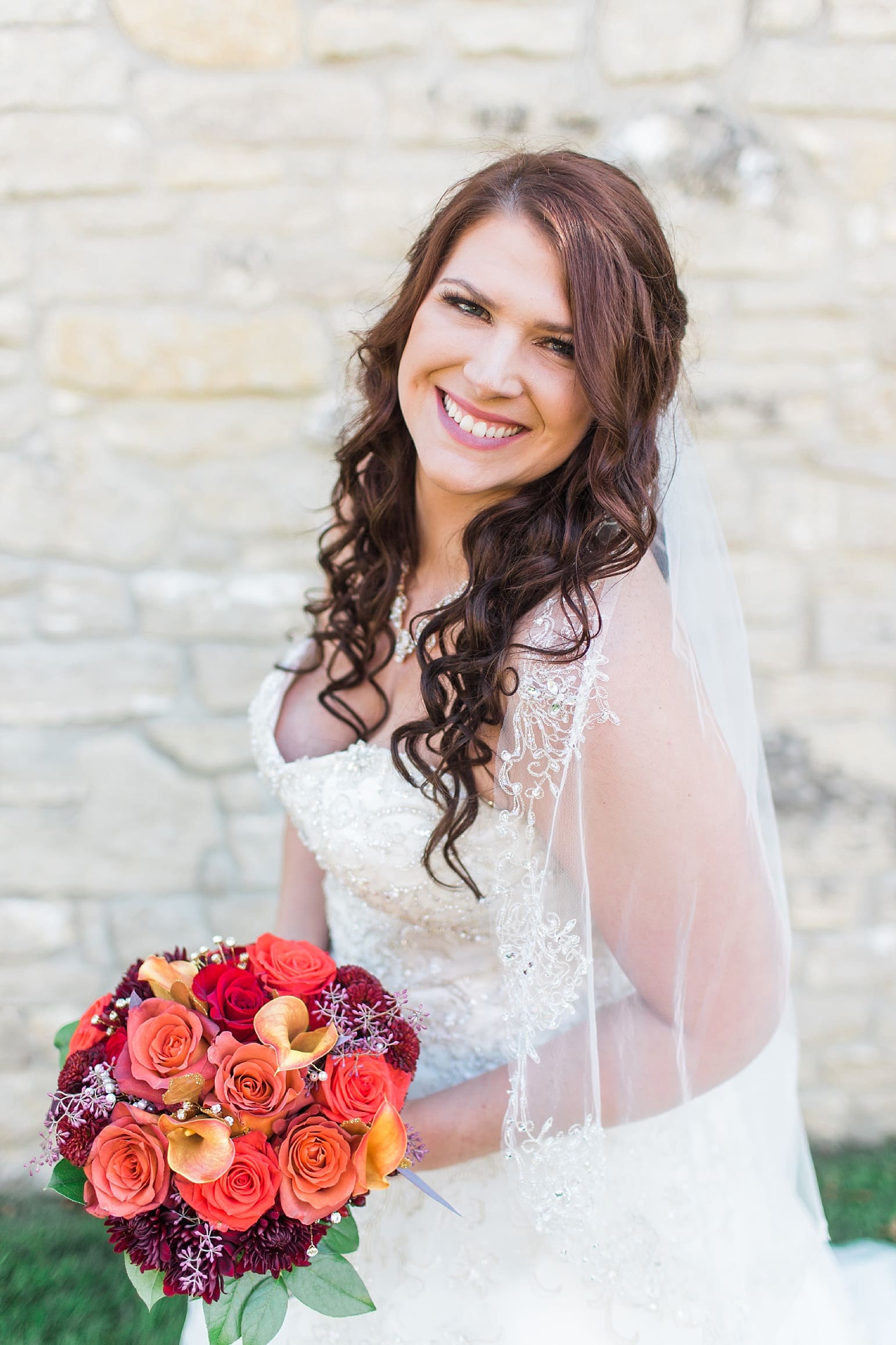 Arielle Peters Photography | Bride holding bouquet next to limestone wall on wedding day in Carmel, Indiana. 