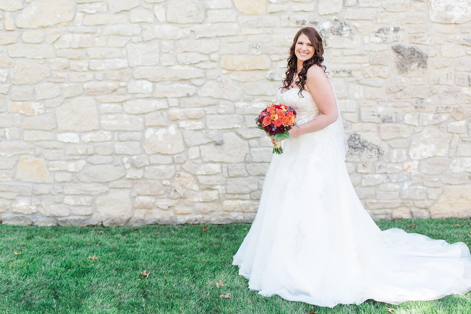 Arielle Peters Photography | Bride holding bouquet next to limestone wall on wedding day in Carmel, Indiana. 
