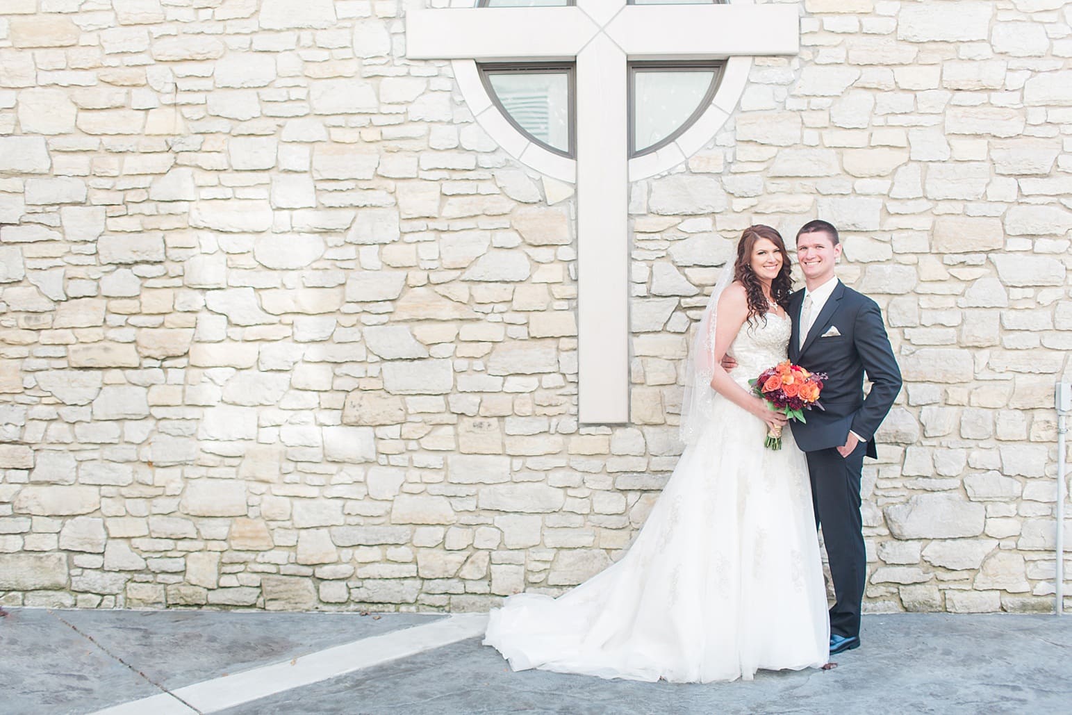 Arielle Peters Photography | Bride and groom next to limestone church on wedding day in Carmel, Indiana. 