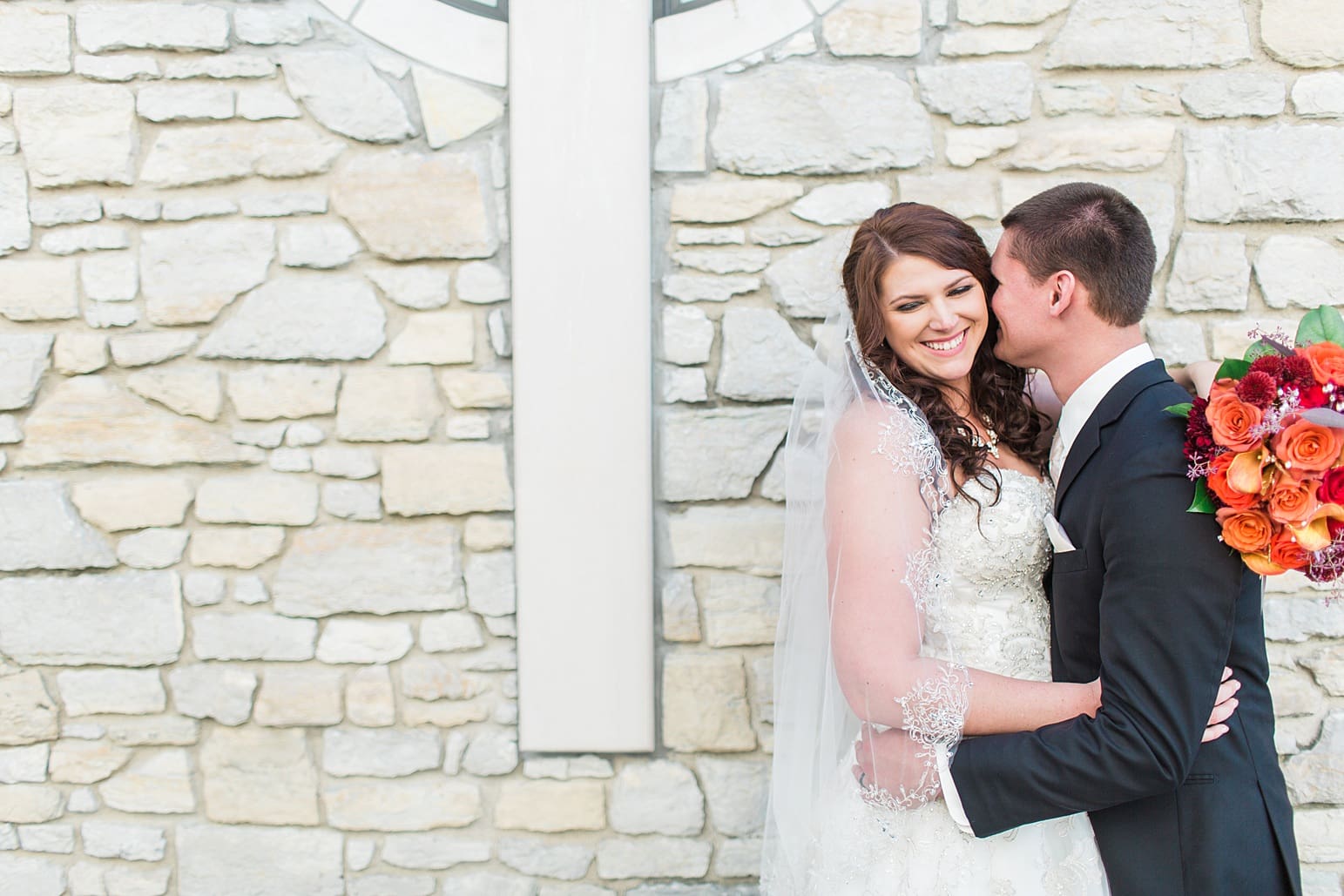 Arielle Peters Photography | Bride and groom next to limestone church on wedding day in Carmel, Indiana. 